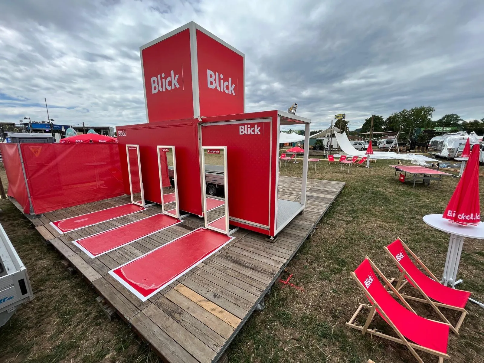 Roter Blick Cube mit Würfel auf dem Dach, drei Spiegel auf roten Teppichen, Liegestühle und Ping-Pong-Tisch auf der Wiese