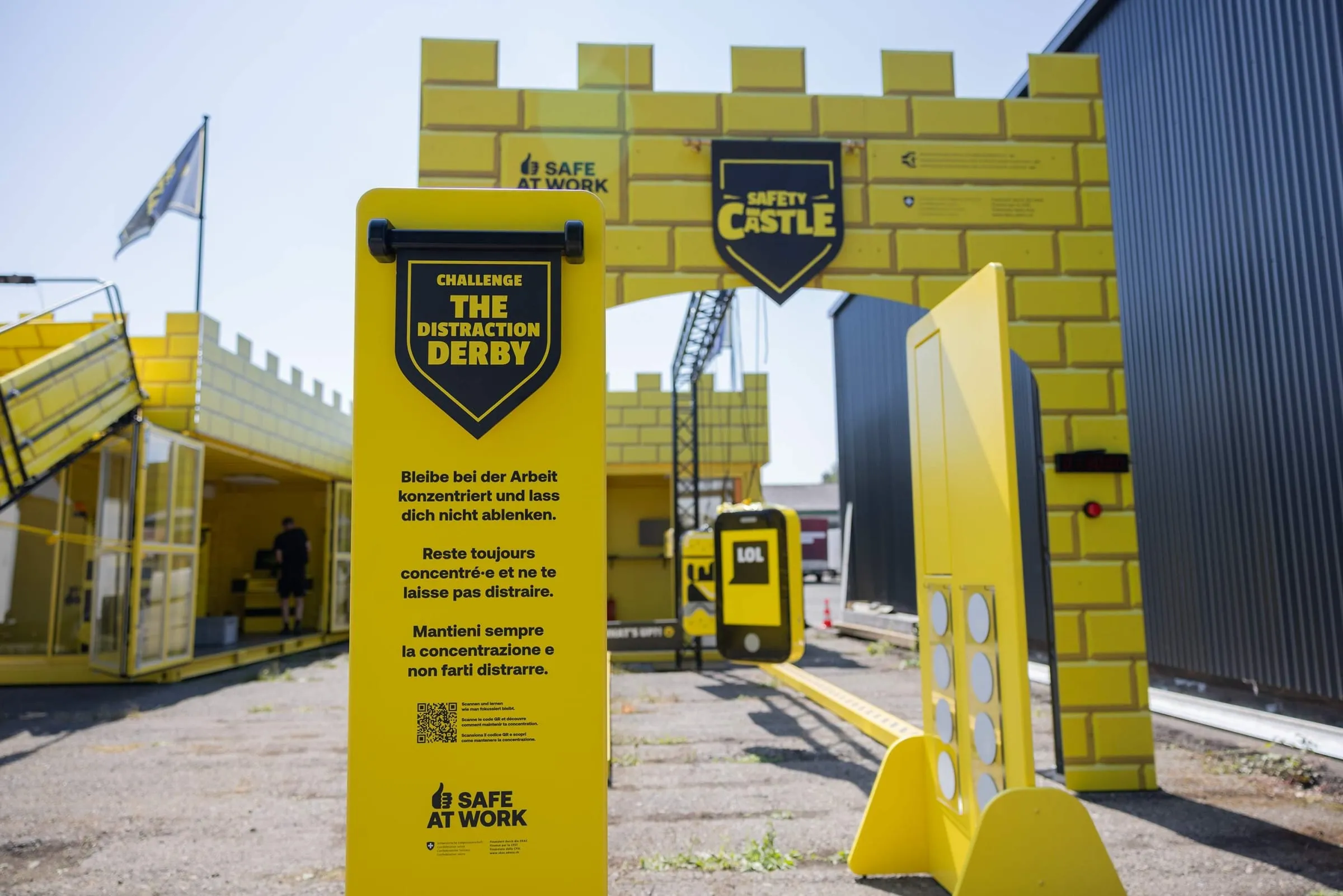 «The Distraction Derby» board in front of the castle gate, behind it the large phone emoji with «LOL» and a yellow buzzer post