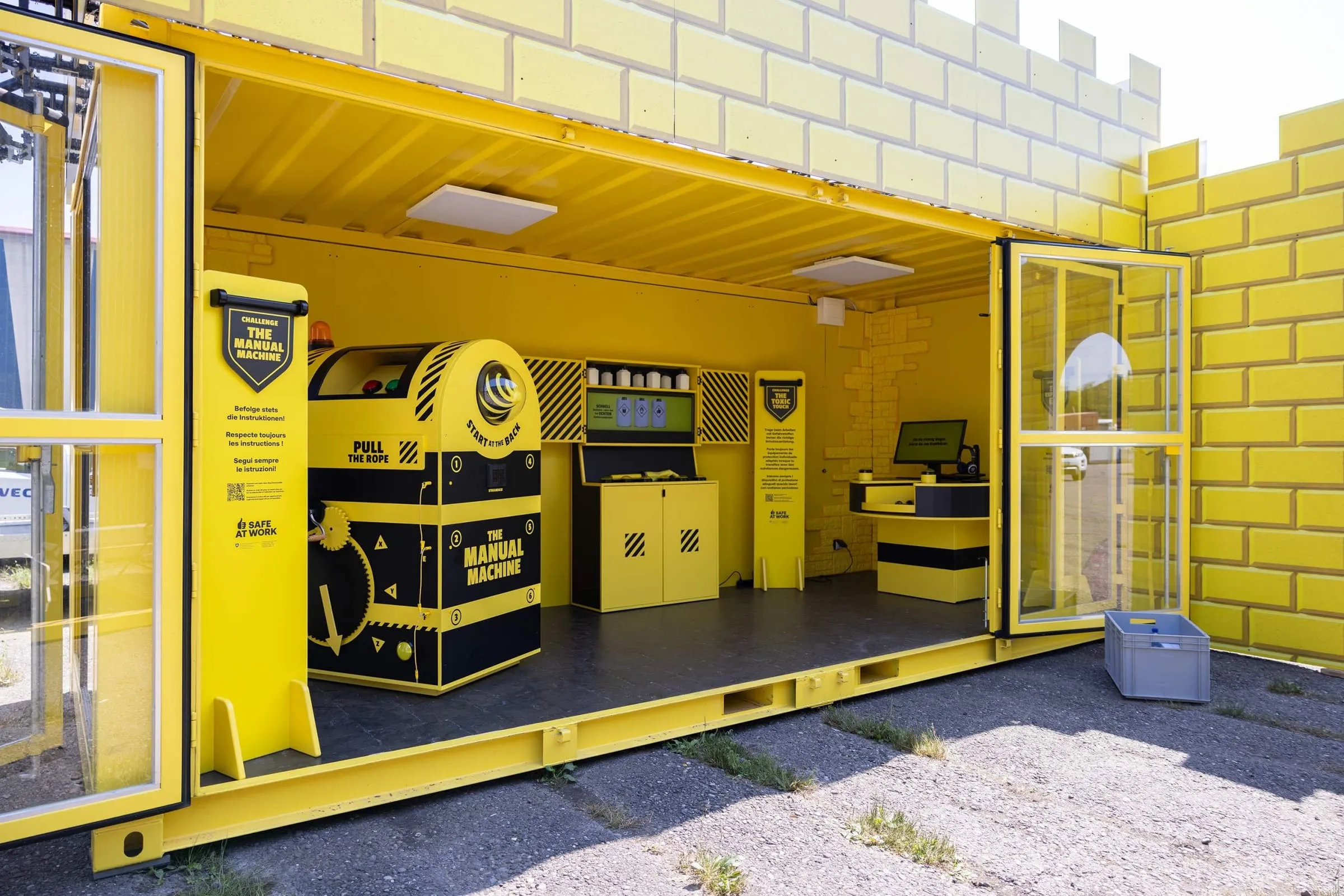 Open yellow container with the Manual Machine, Toxic Touch and Expert's Eye stations, brick-effect facade with battlements outside