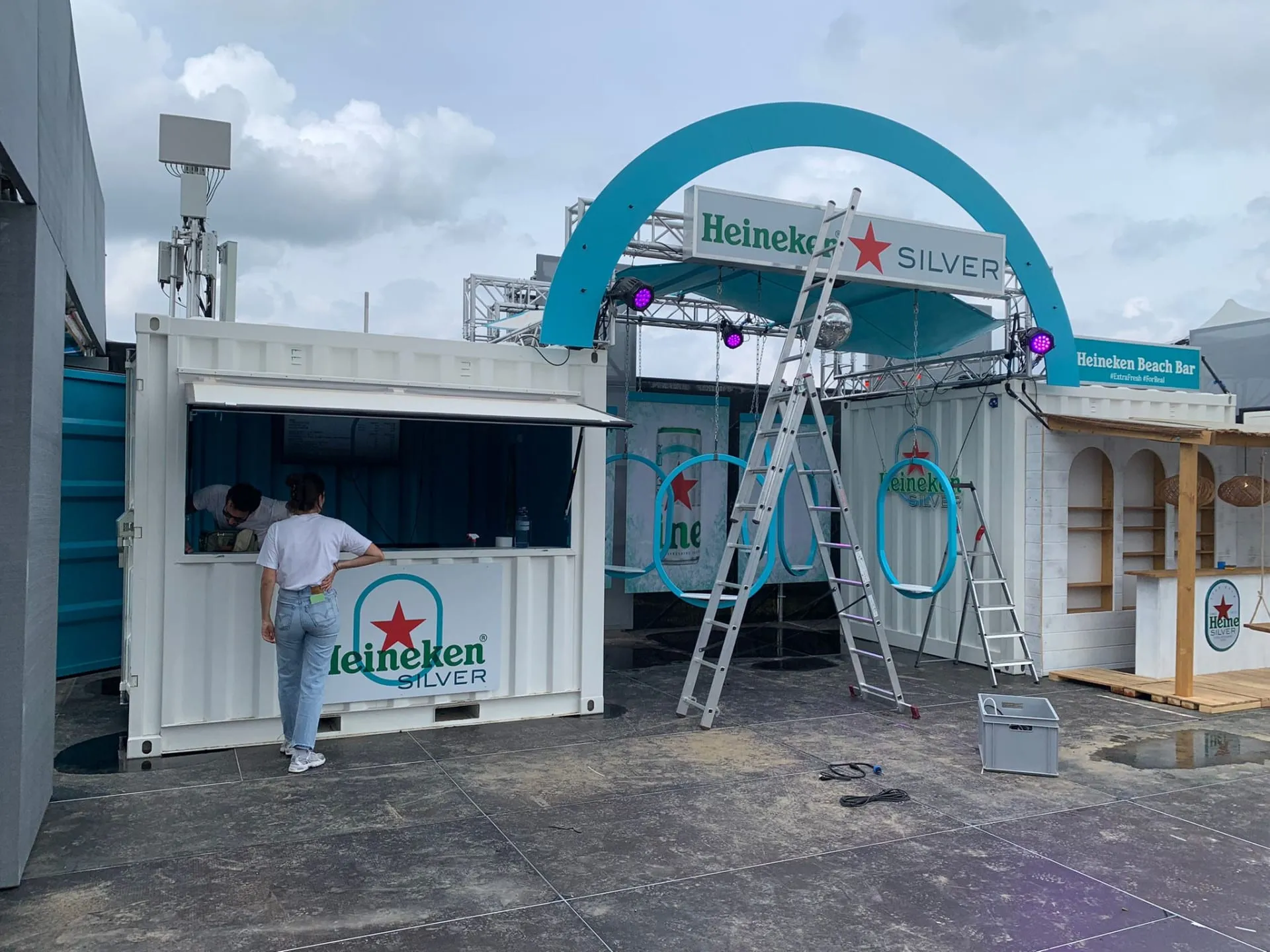 Fast fertiger Stand: Container mit Ausschank, türkiser Bogen mit Discokugel, Ringschaukeln und Beach Bar, Leitern davor