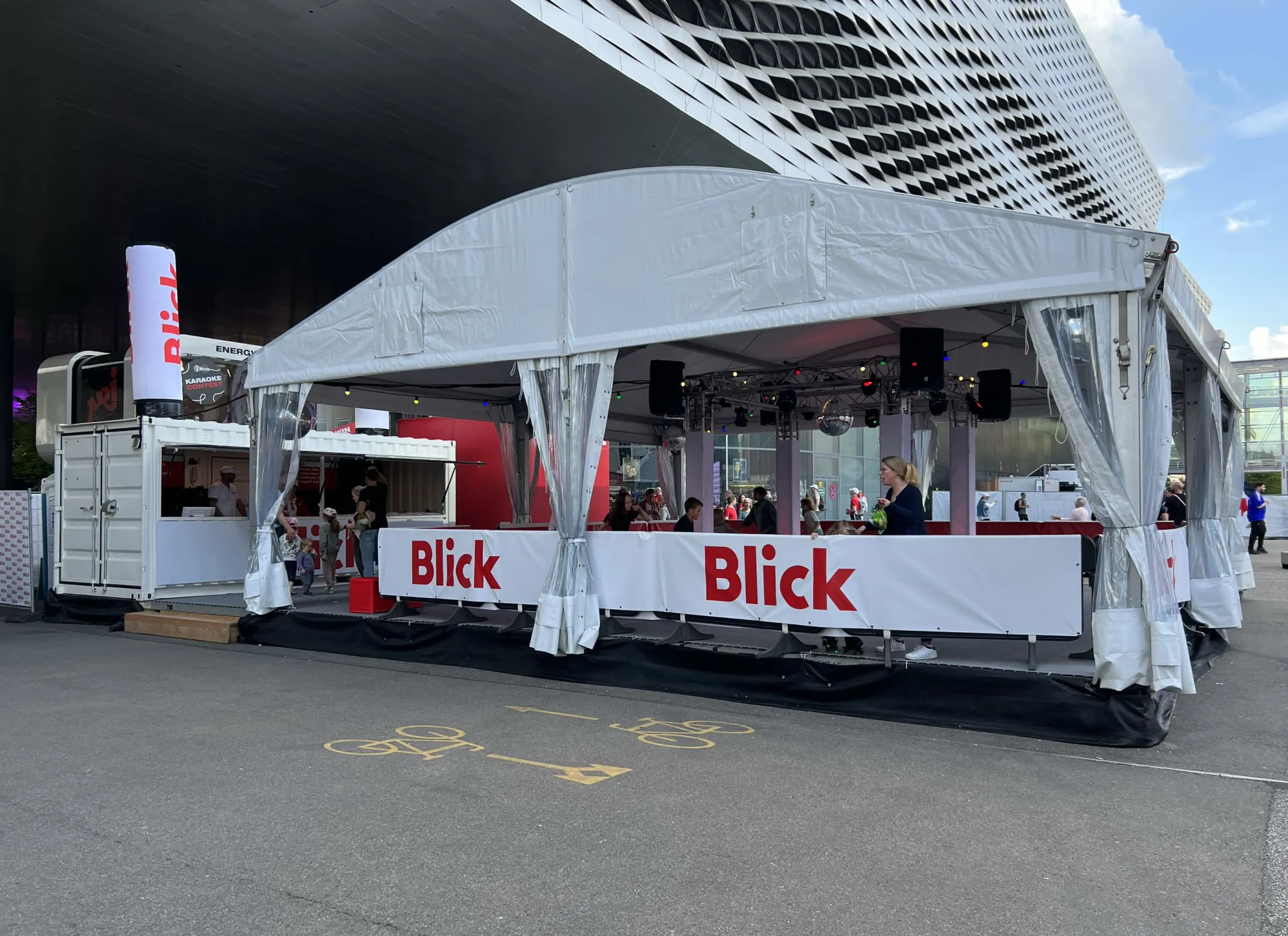 Blick-Zelt mit Rollschuhdisco, Traversen mit Lichttechnik, Discokugel und weissem Container mit Blick-Säule vor der Messe Basel