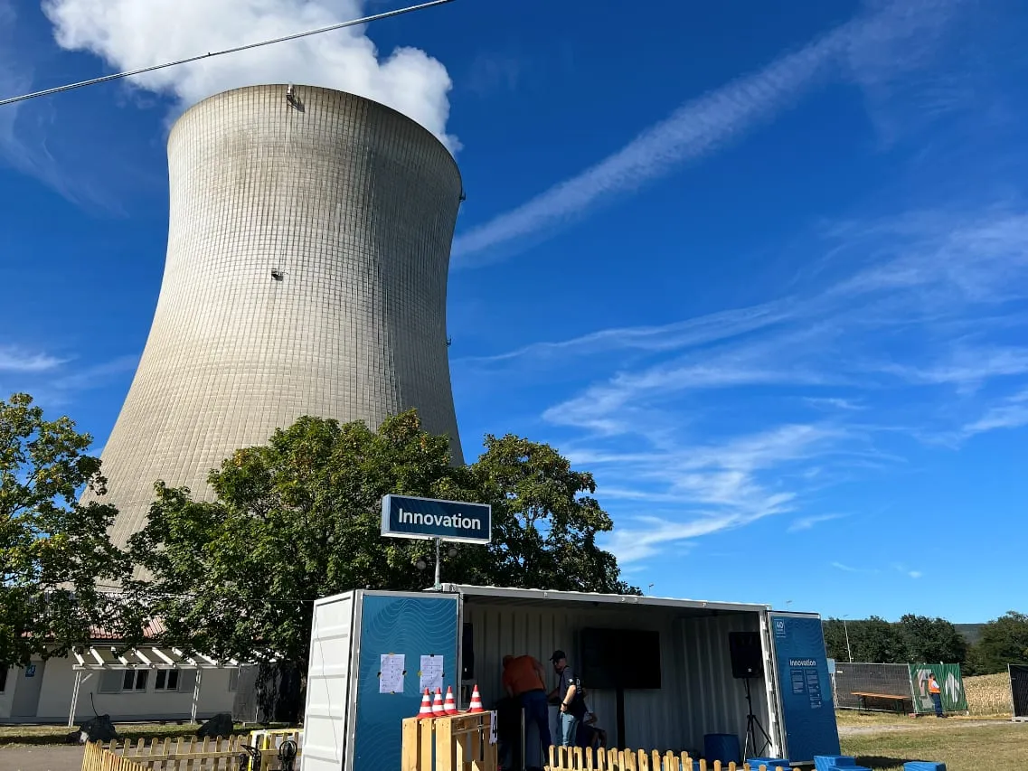 Cooling tower at Leibstadt nuclear power plant above the open Innovation container, with visitors and a wooden fence