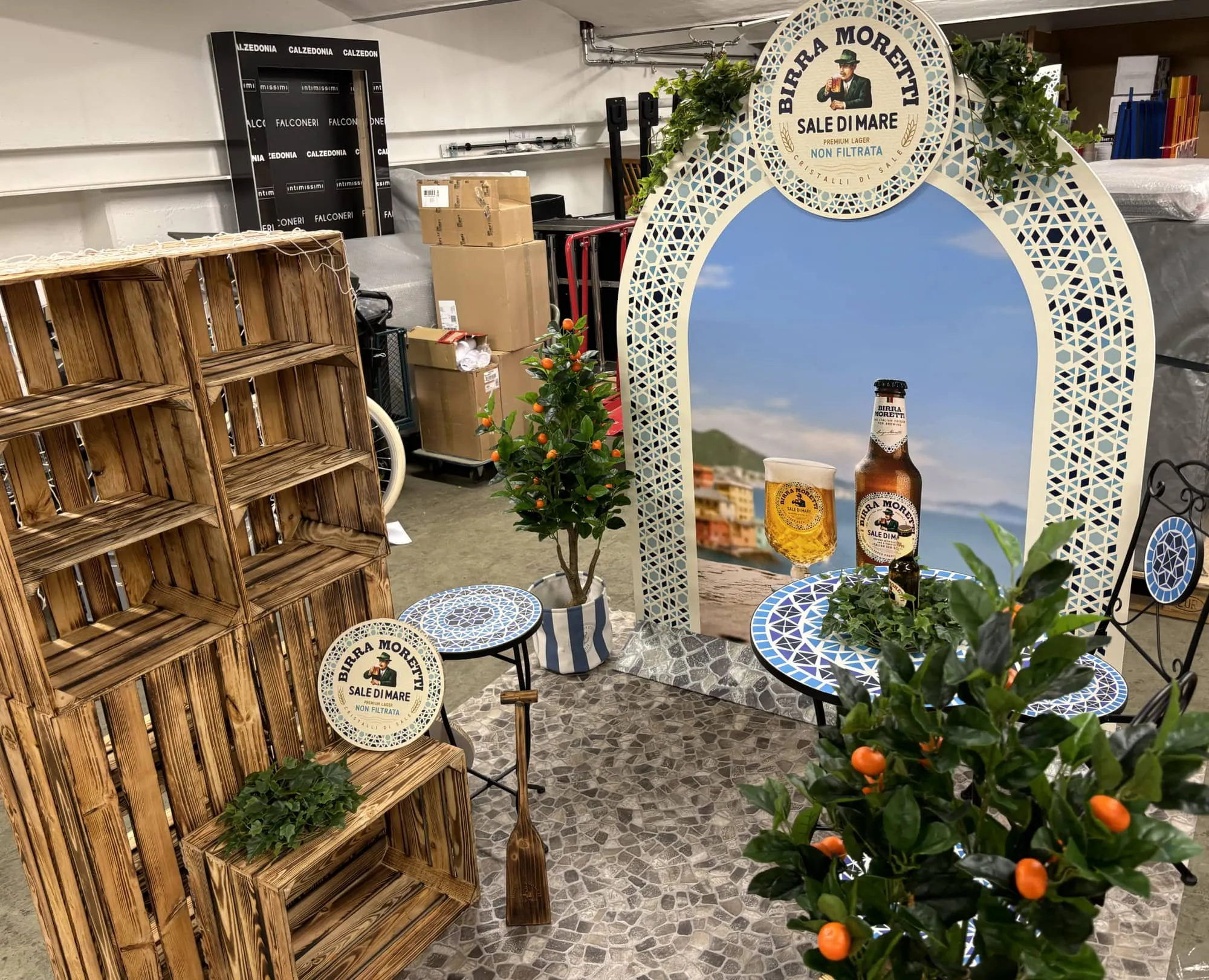 Seitenansicht des Corners mit leeren Holzkistenregalen, Torbogen, Mosaiktisch und Holzpaddel