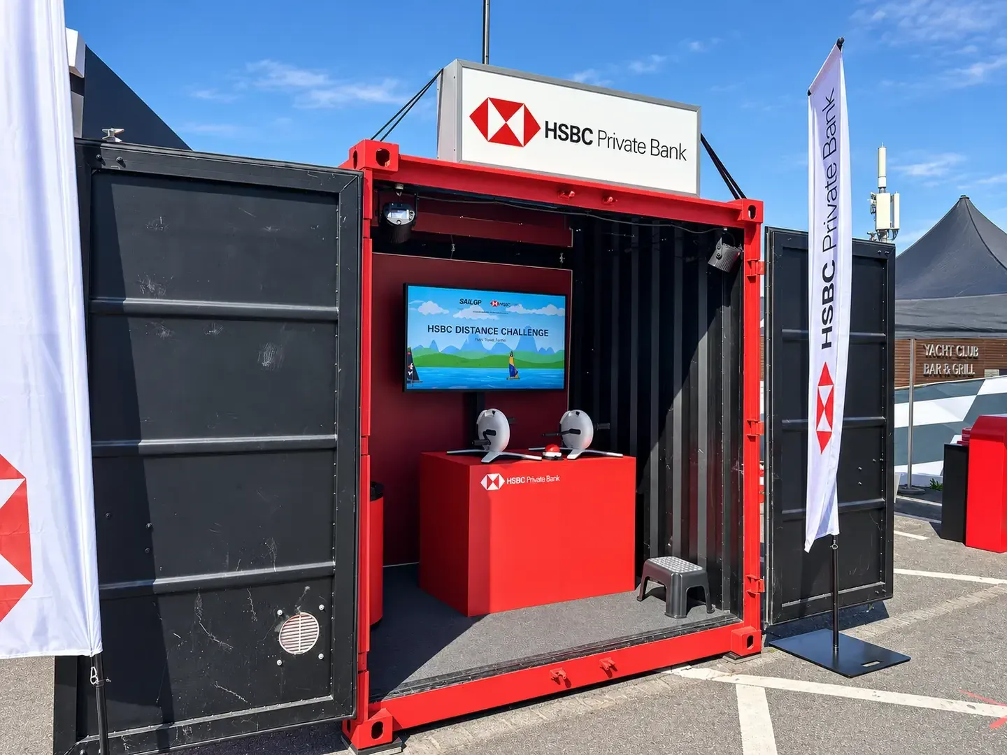 Rot-schwarzer 10-Fuss-Container von HSBC mit geöffneten Türen, drinnen ein Screen mit der «HSBC Distance Challenge» und ein Ruderergometer auf rotem Podest
