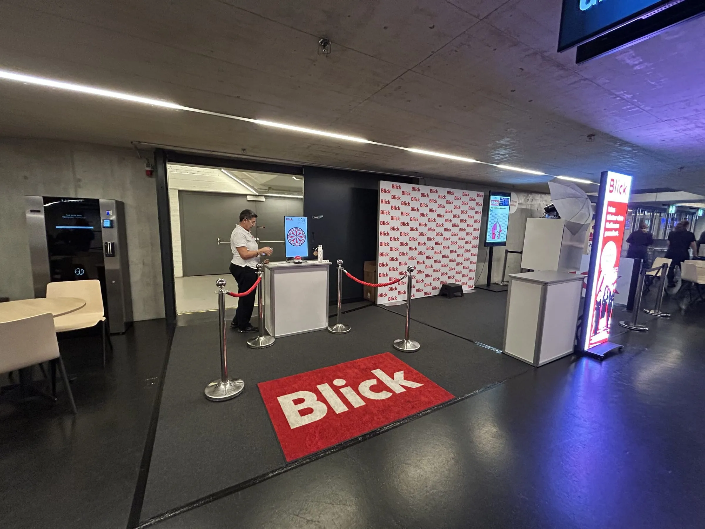Blick-Stand im Foyer des Hallenstadions mit Glücksrad-Theke, roten Kordeln, Logowand und Blick-Teppich