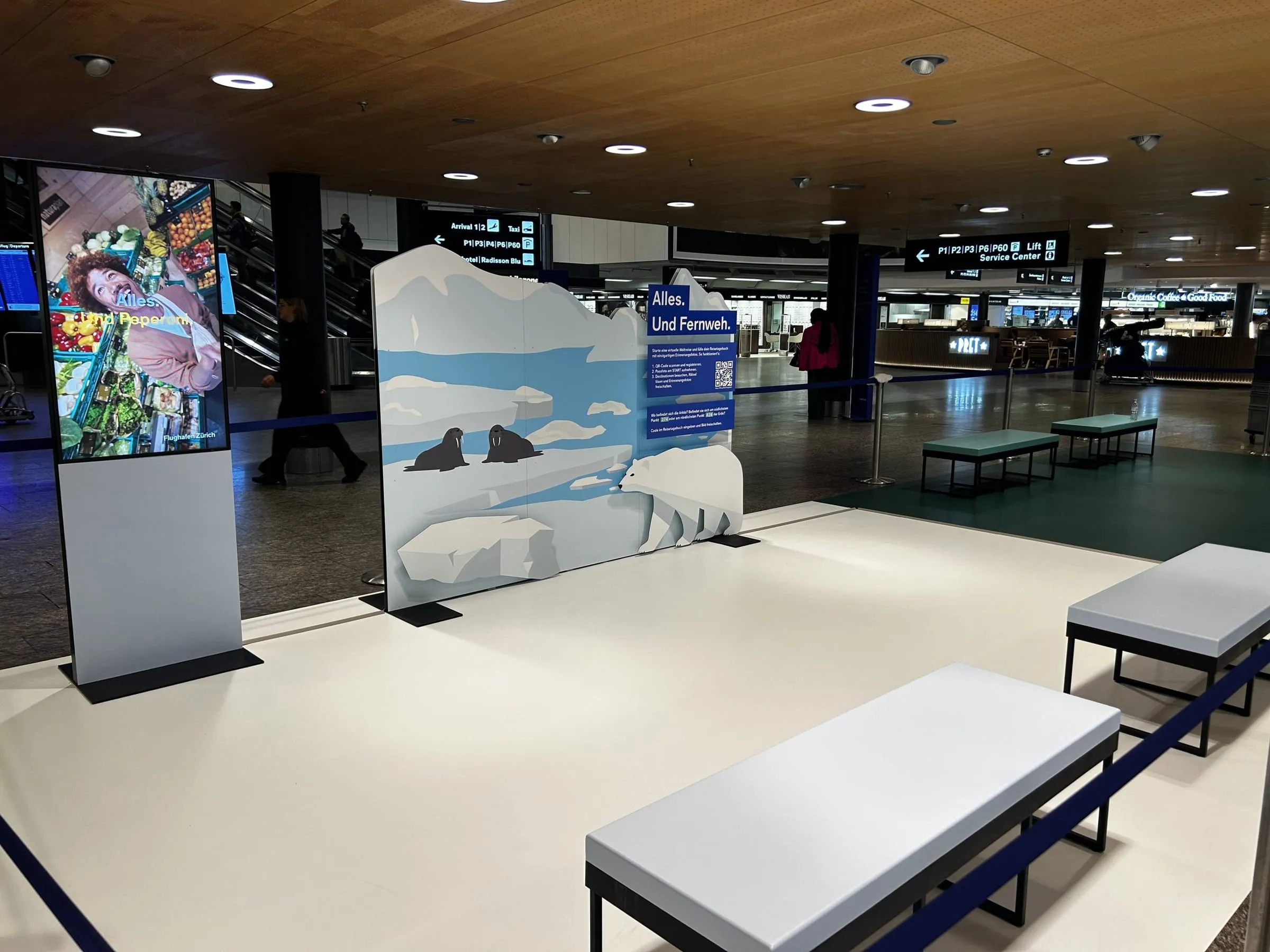 Photo station with polar-bear and walrus scenery, an «Alles. Und Fernweh.» sign and a screen at Zürich Airport