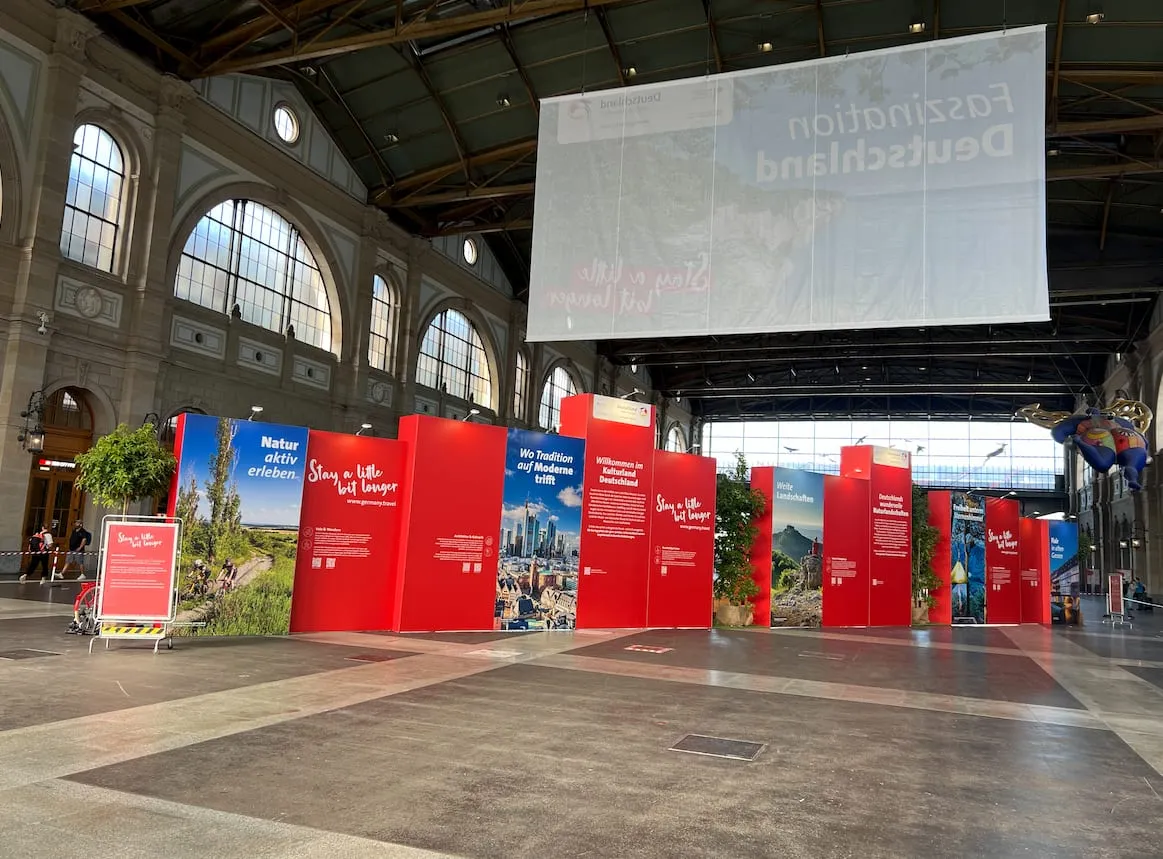 Rückseite der roten Messewände mit Texttafeln zu Natur, Kultur und Landschaften unter dem XXL-Banner