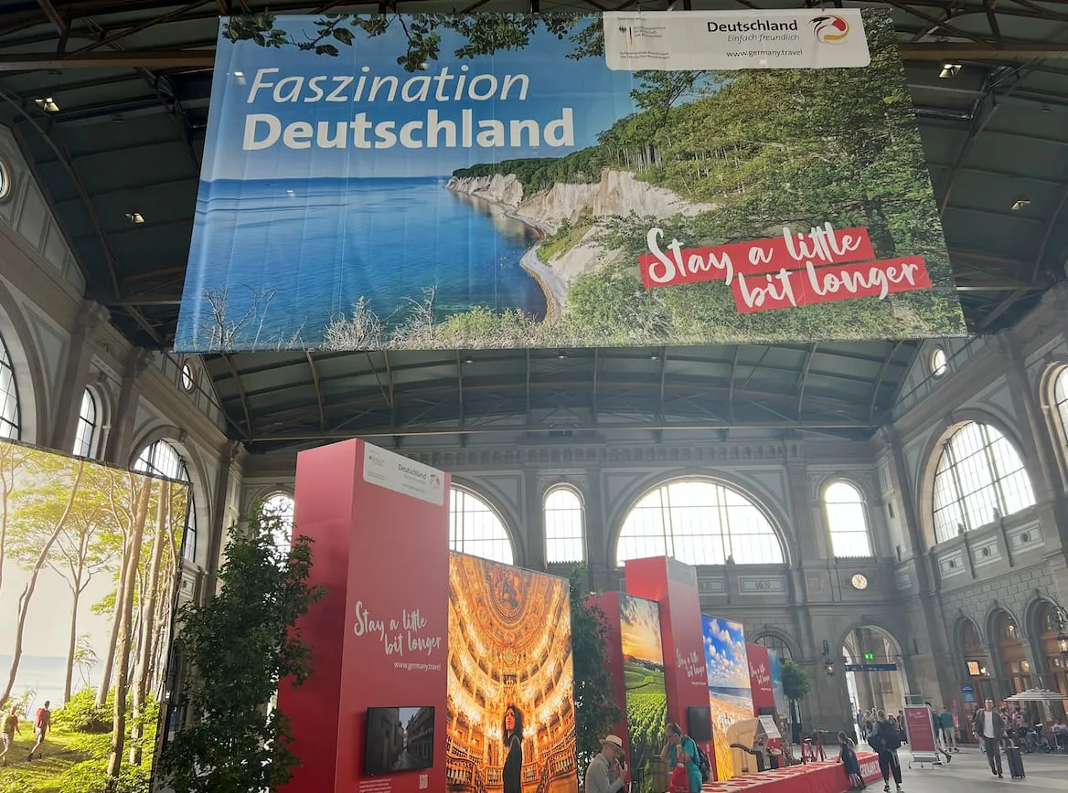 XXL-Banner «Faszination Deutschland» mit Kreidefelsen hängt über den roten Messewänden von der Hallendecke