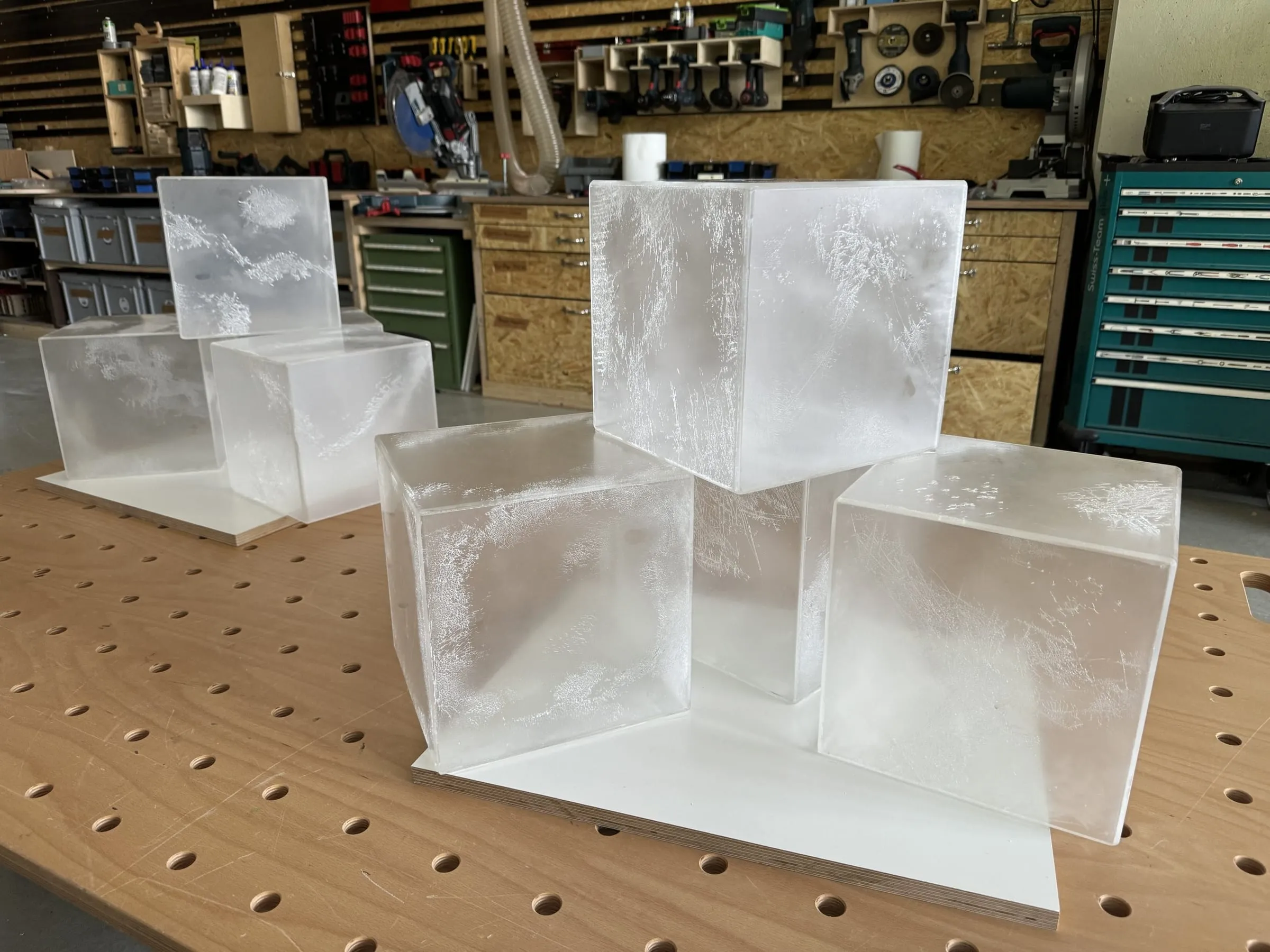 Sechs grosse Eiswürfel aus mattem Acryl mit Frostmuster auf dem Werktisch in der Werkstatt