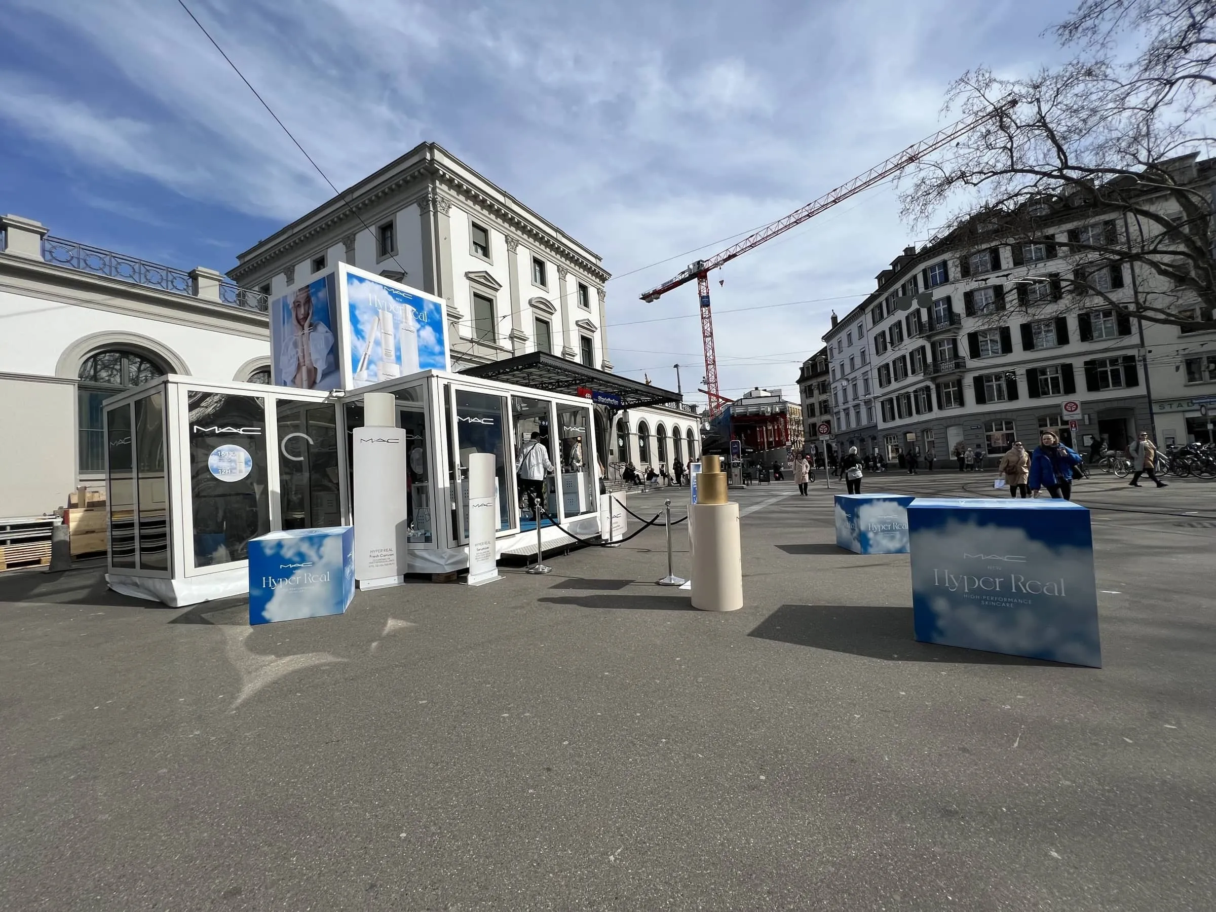 White Promocube with glass walls, cloud-patterned cubes and oversized product bottles outside Stadelhofen station