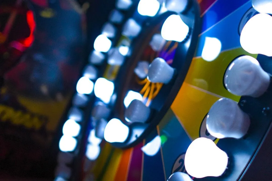 Close-up of an analog wheel of fortune with glowing light bulbs and coloured segments