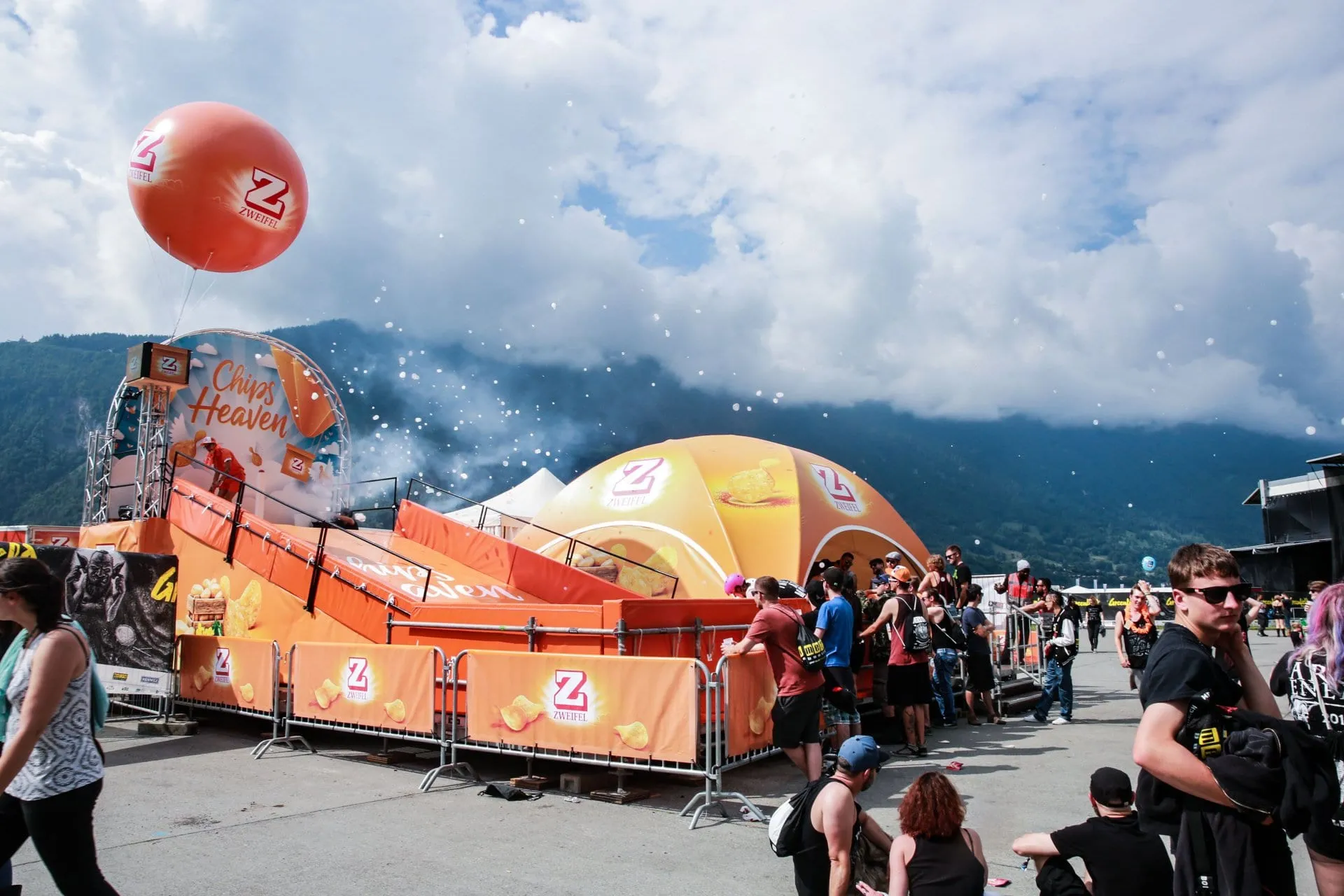 Der Chips Heaven von aussen: orange Rampe, Bogen, roter Zweifel-Ballon und Kuppelzelt vor Bergkulisse