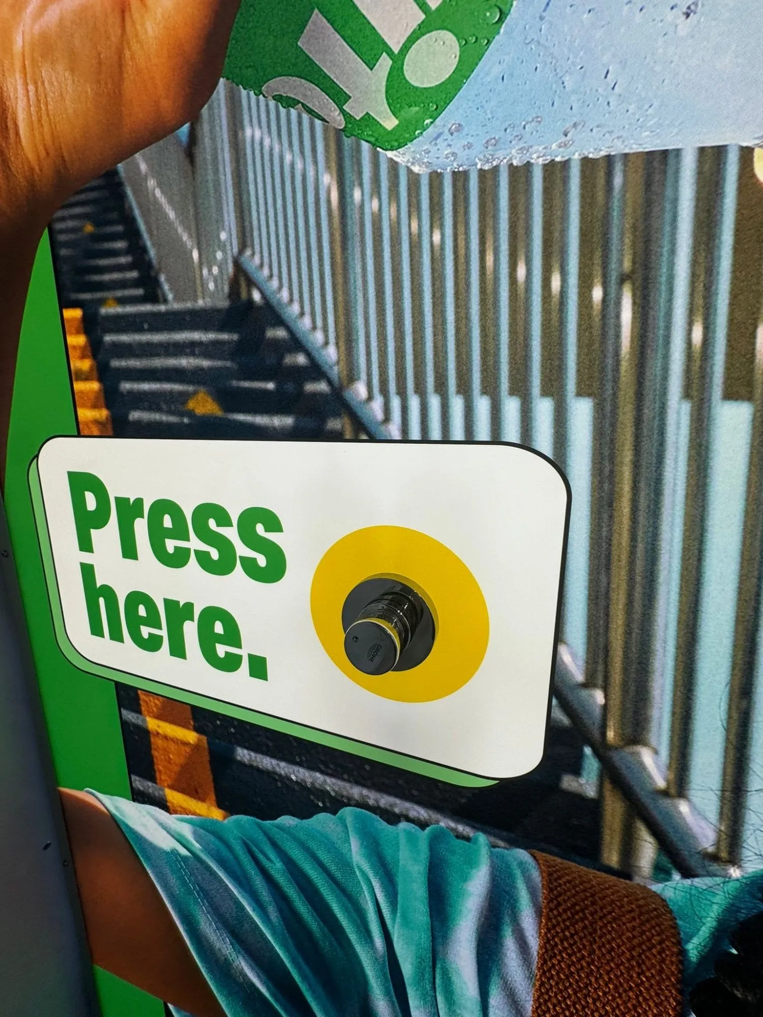 Nahaufnahme des Druckknopfs «Press here» in einem gelben Kreis auf dem Sprite-Plakat
