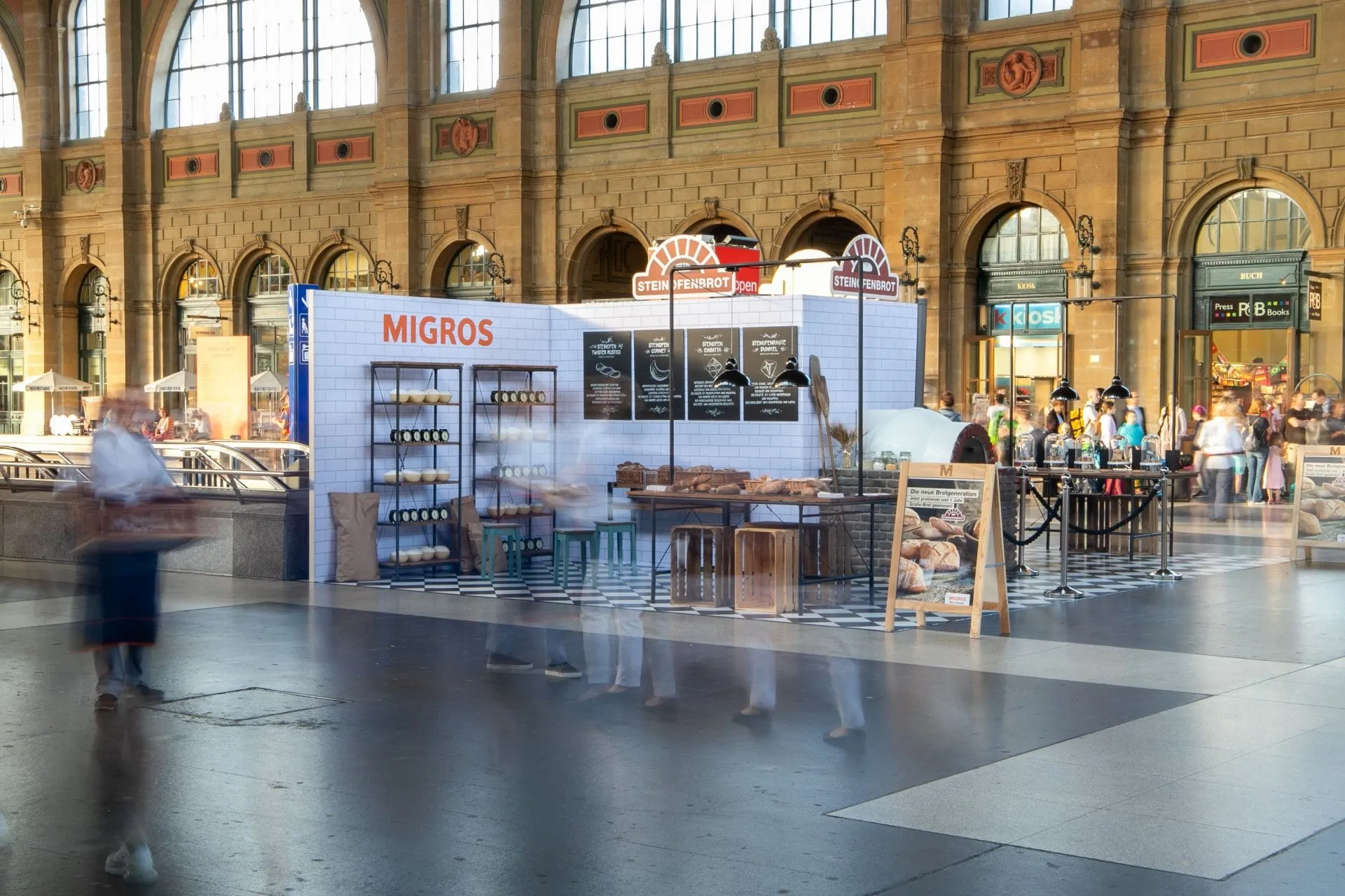 Stone-oven bread stand with tiled walls, shelves, blackboards and an oven in the hall of Zürich main station