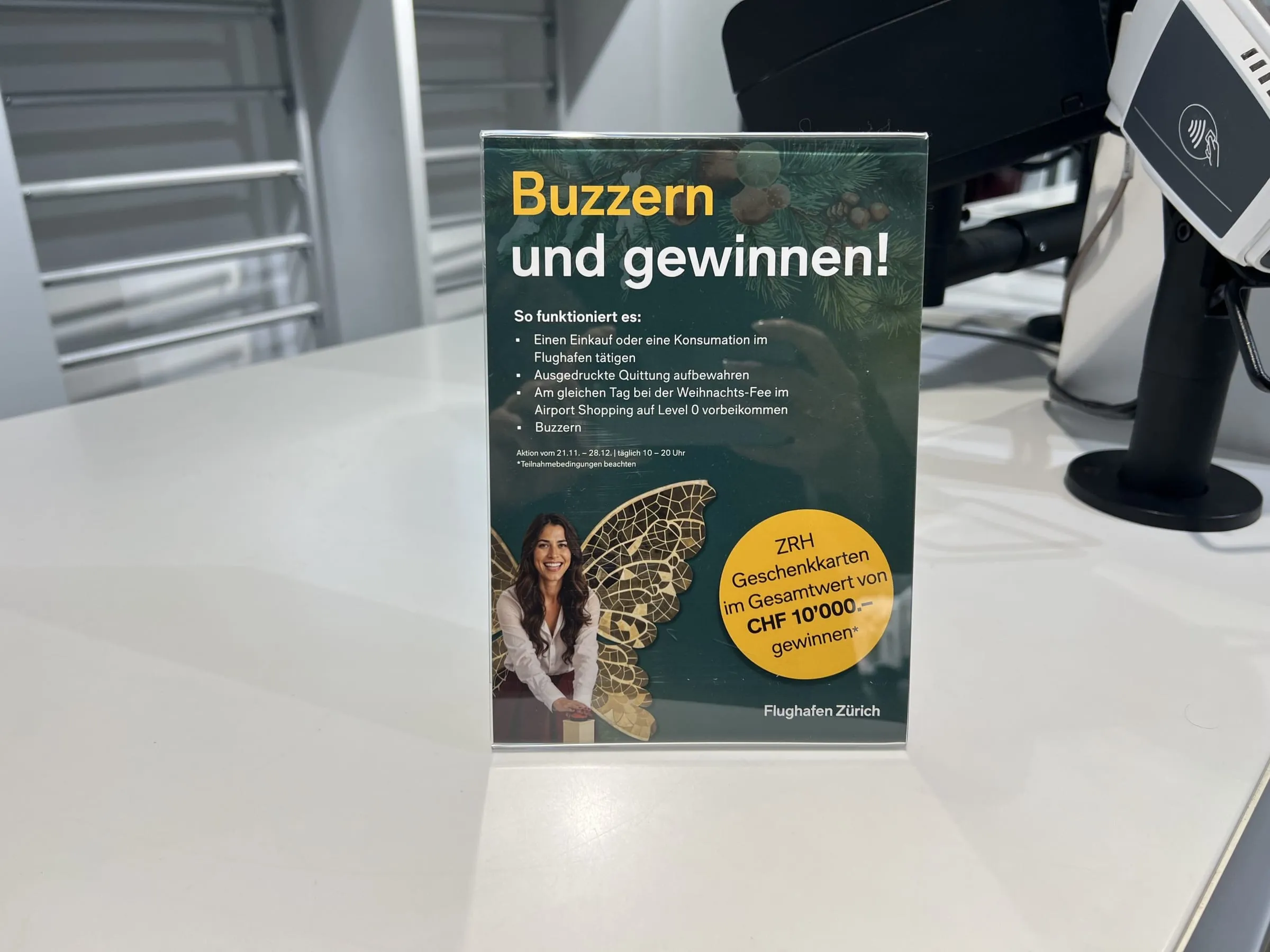 Tischaufsteller «Buzzern und gewinnen!» mit Weihnachtsfee-Motiv und CHF-10'000-Störer neben einem Kartenterminal