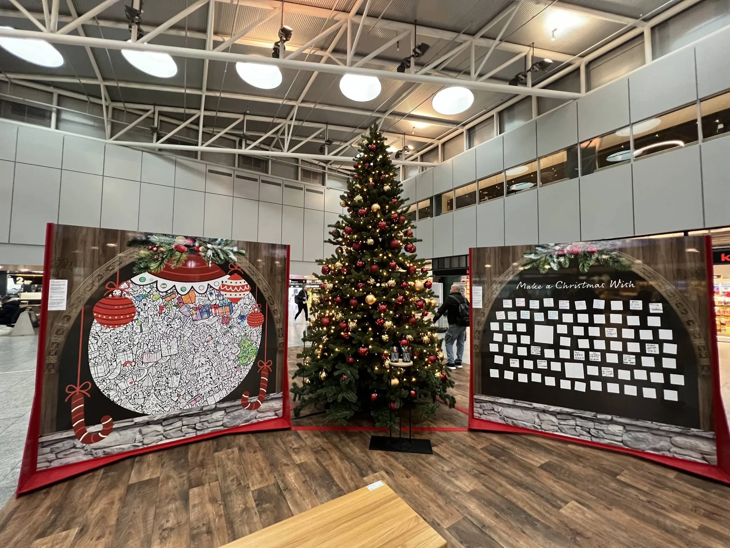 Mandala-Wand mit roten Christbaumkugeln und Wünsche-Wand «Make a Christmas Wish» mit beschriebenen Zetteln, dazwischen der Weihnachtsbaum