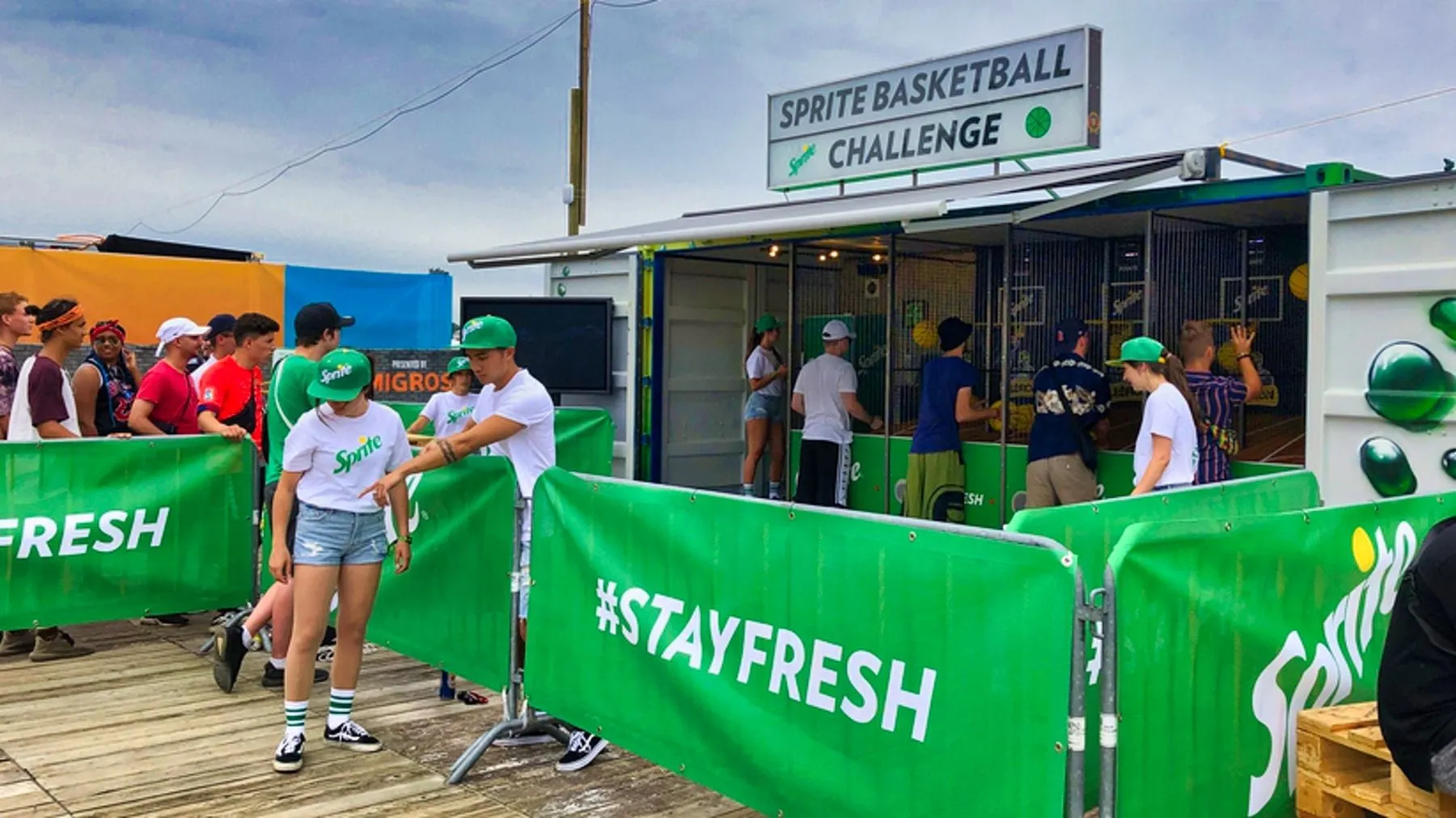 Promotional staff in Sprite shirts outside the container, players at hoops behind mesh panels and a «#Stayfresh» banner