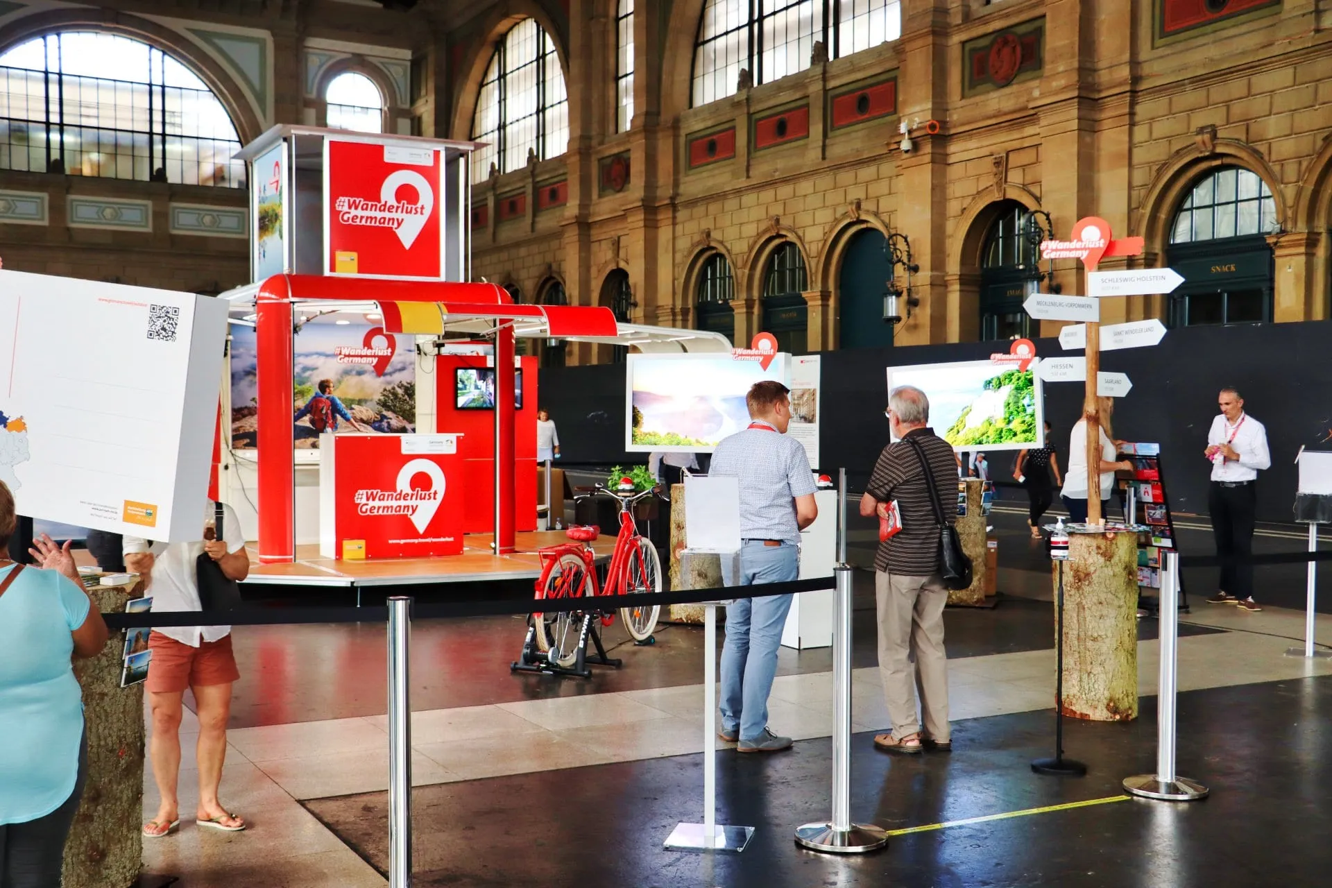 Red #Wanderlust Germany cube, red bicycle, giant postcard and signpost in the hall of Zürich main station
