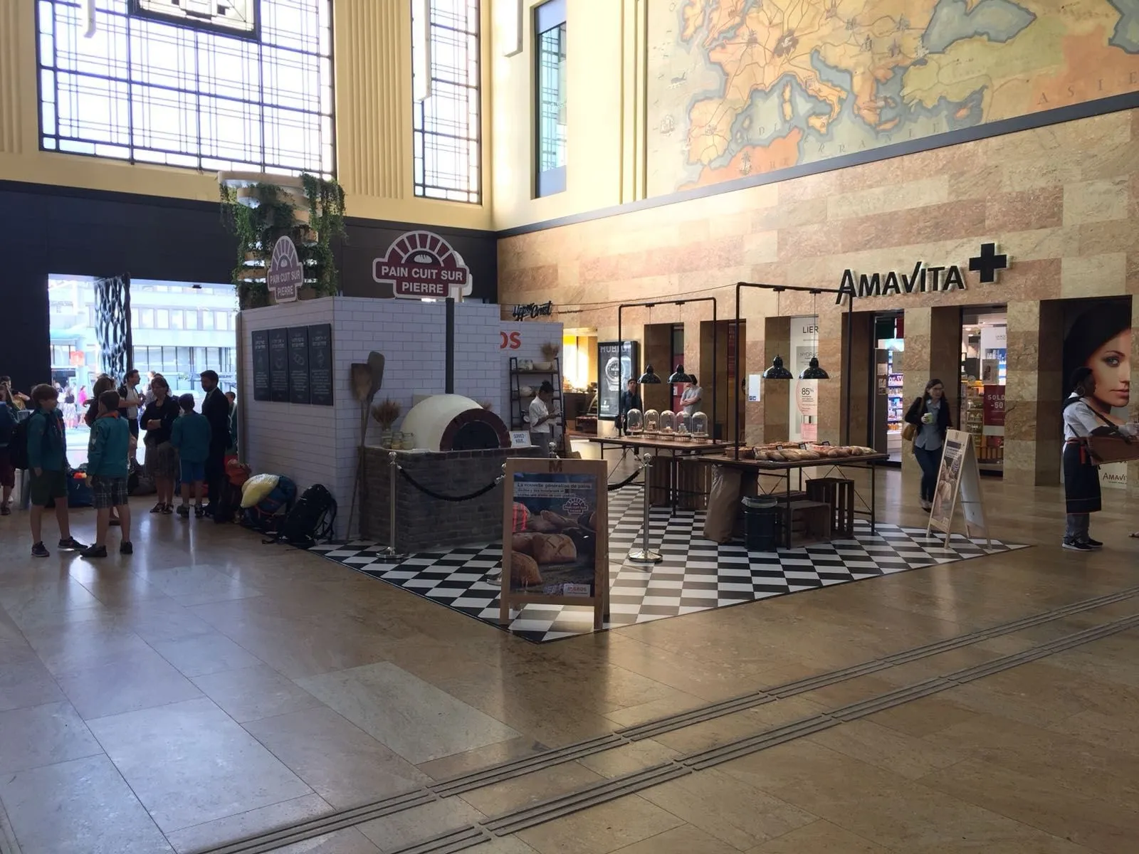 Stand «Pain cuit sur pierre» mit Steinofen und Tischen in einer Bahnhofshalle in Genf