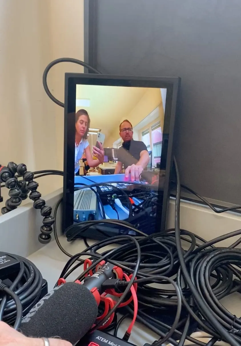 Monitor mit Testaufnahme zweier Personen, davor Mikrofon, Kabel und ATEM-Mini-Videomischer im Büro