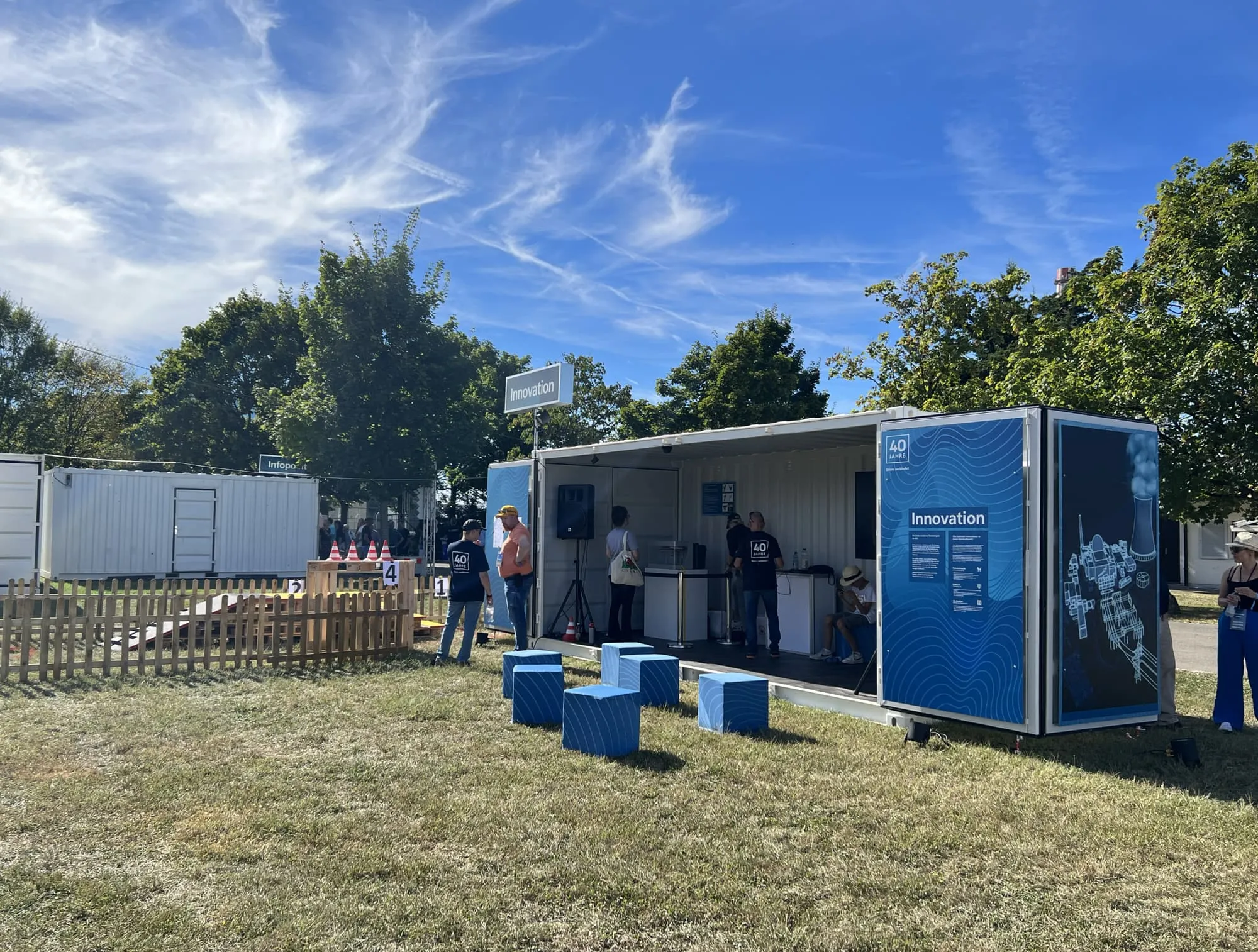 Innovation-Container mit hellblauen Sitzwürfeln, Holzzaun und Parcours aus Paletten bei Tag