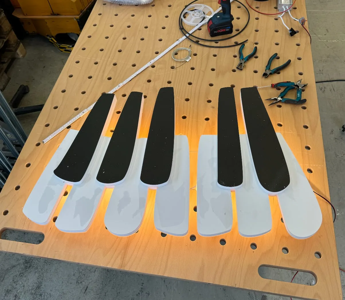 Klaviertasten-Element mit indirekter LED-Beleuchtung auf dem Werktisch, daneben Zangen und Werkzeug