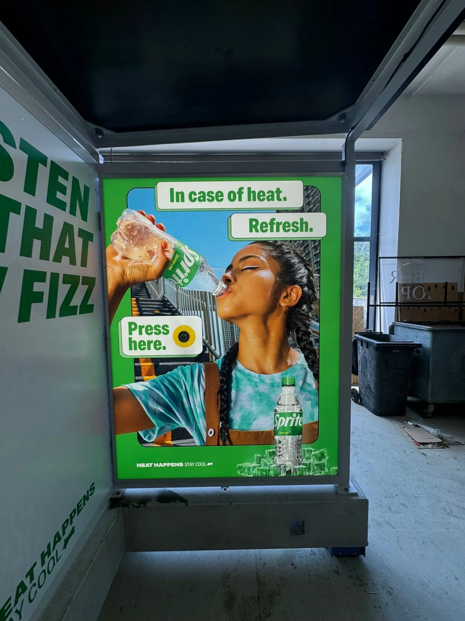 Leuchtplakat mit trinkender Frau, Text «In case of heat. Refresh.» und Knopf «Press here» in der Werkstatt
