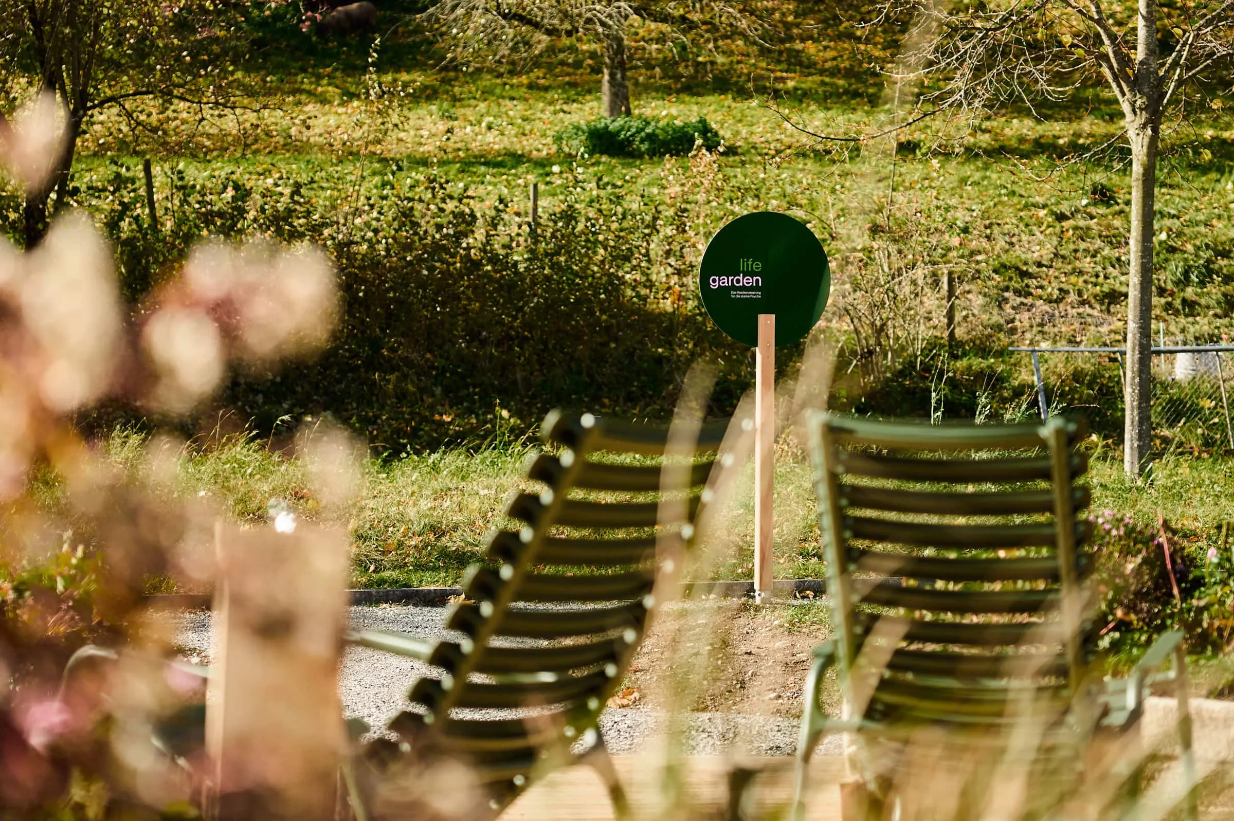 Zwei grüne Schaukelstühle und Lifegarden-Schild, unscharfe Blüten im Vordergrund
