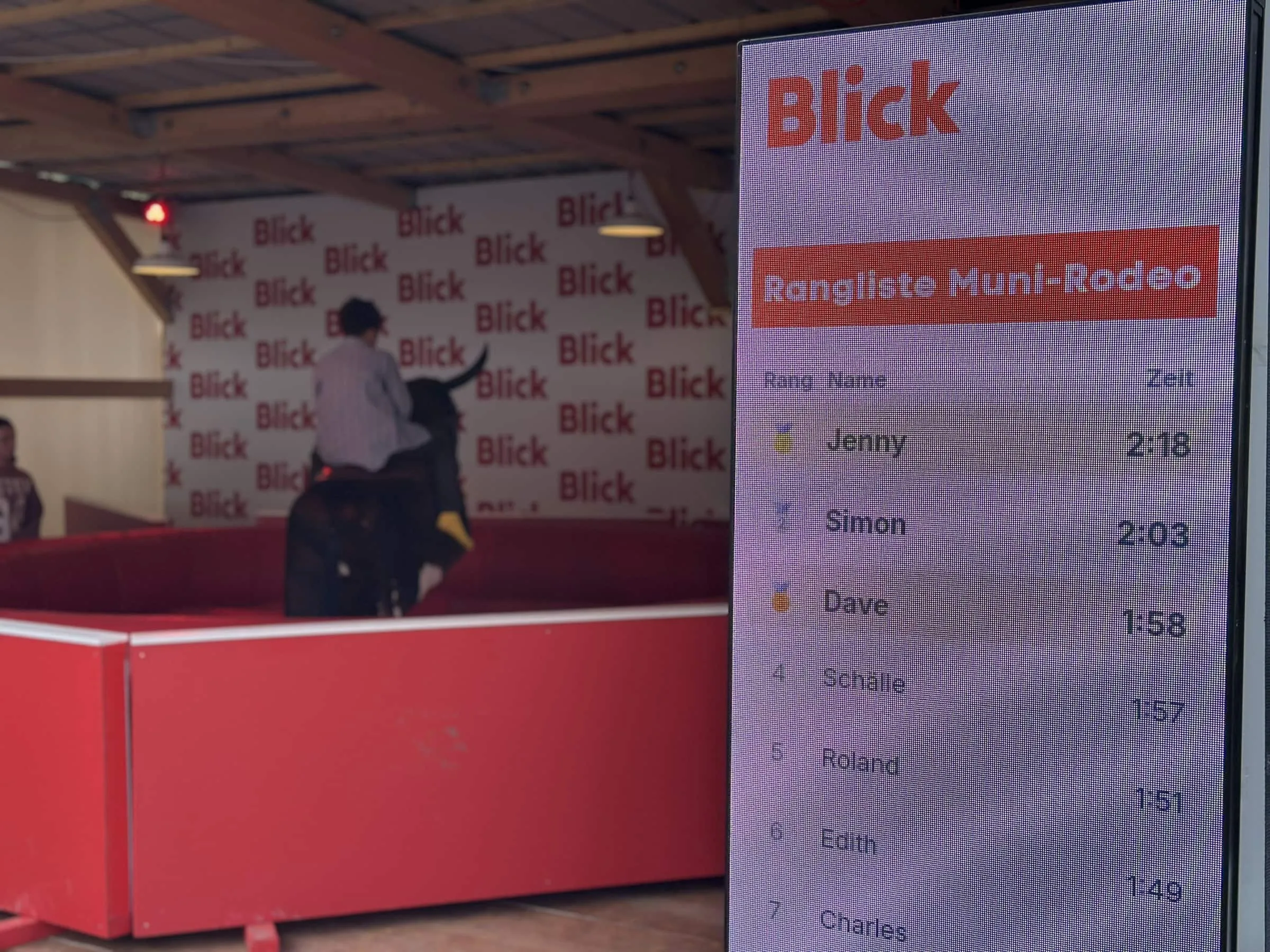 LED-Scoreboard mit Rangliste Muni-Rodeo und Bestzeiten, dahinter unscharf ein Rodeo-Reiter