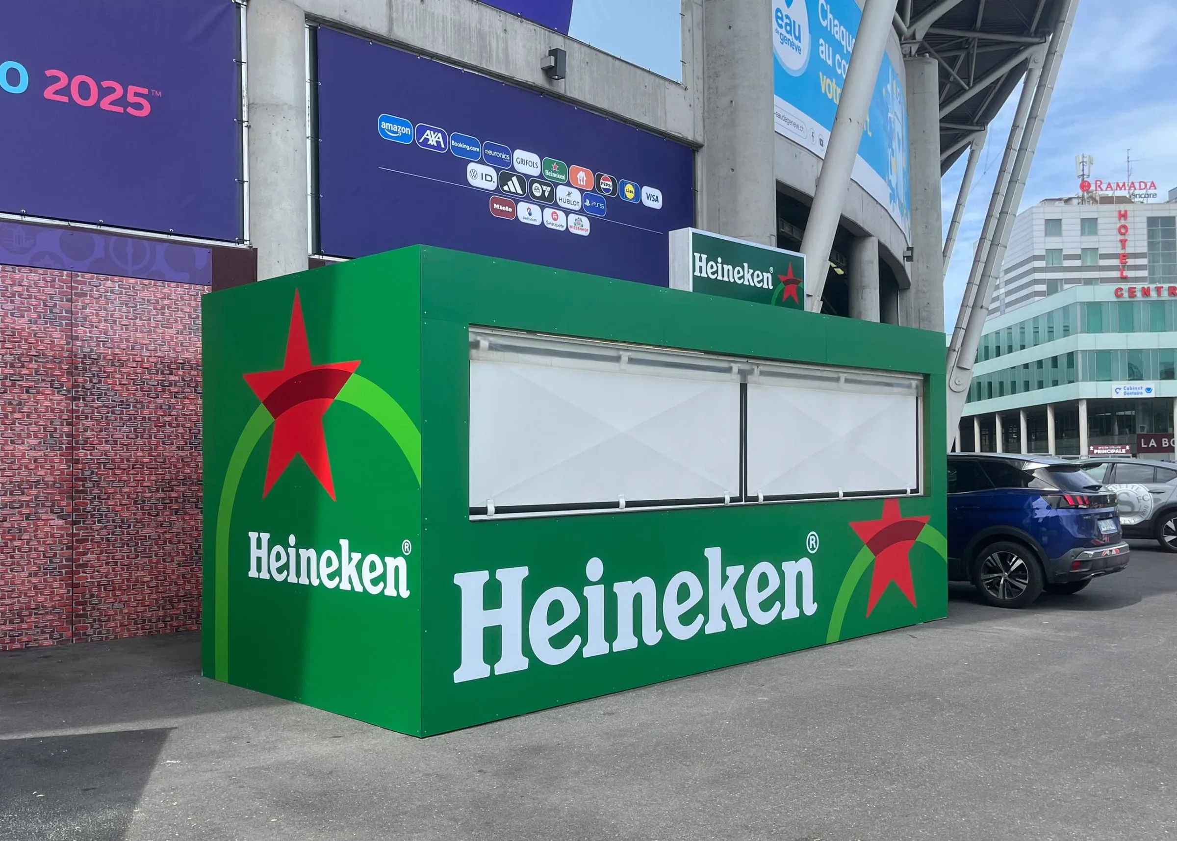 Grüner Heineken-Container mit geschlossenen Klappläden vor dem Stadion in Genf mit EURO-2025-Sponsorenbanner