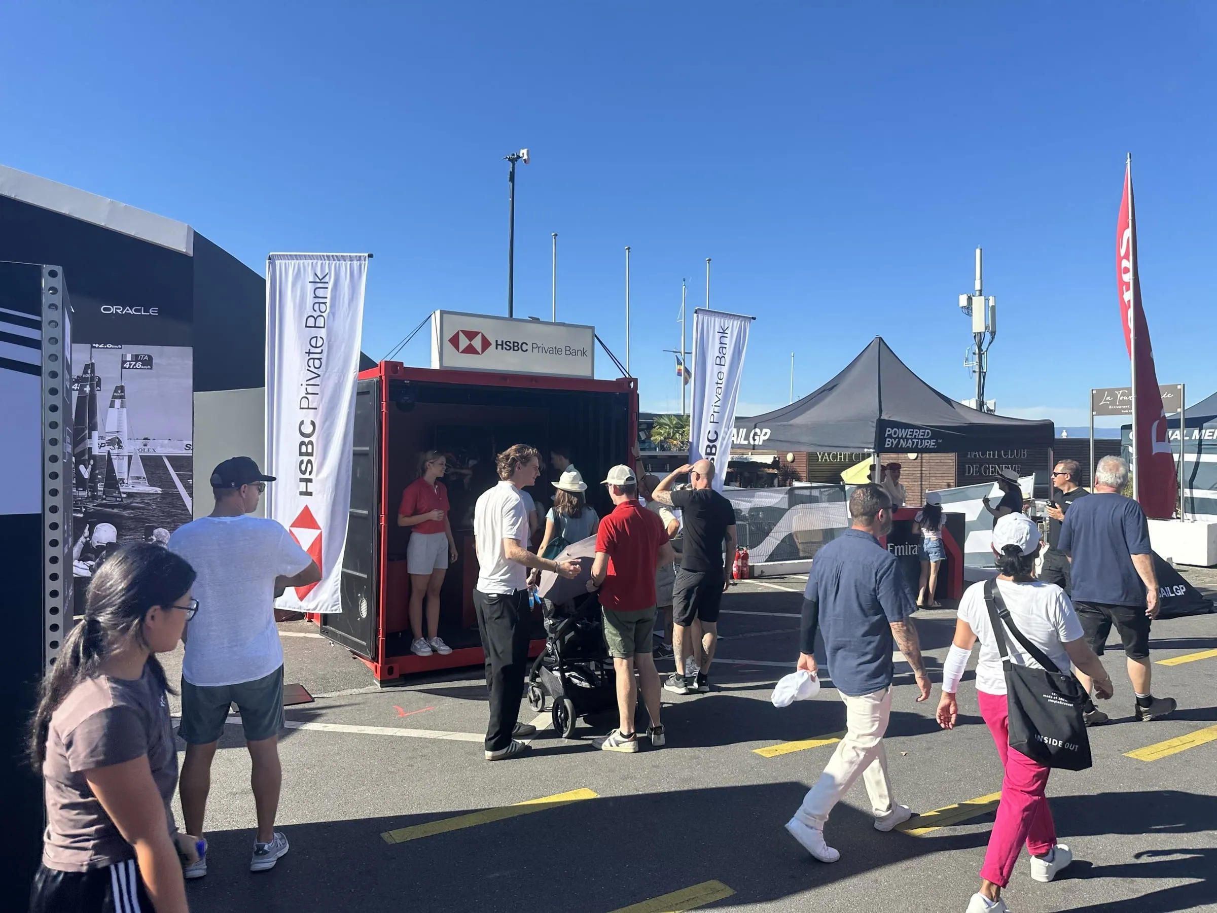 Besuchende vor dem HSBC-Container am SailGP Genf, Promotorin im roten Polo im Eingang