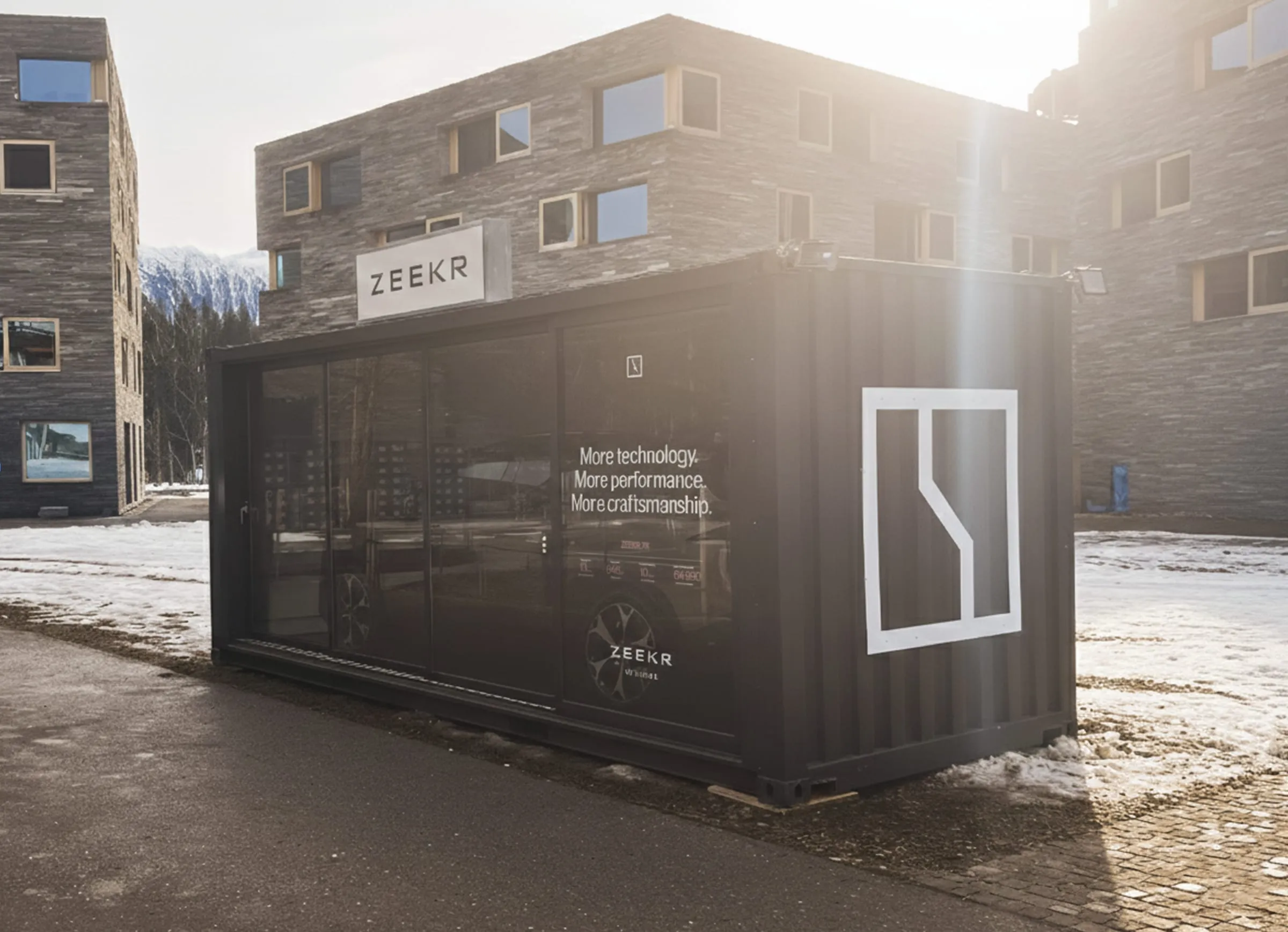 Dunkelgrauer Zeekr-Container mit verglaster Längsseite und Schriftzug «More technology. More performance. More craftsmanship.» im Gegenlicht vor Steinfassaden