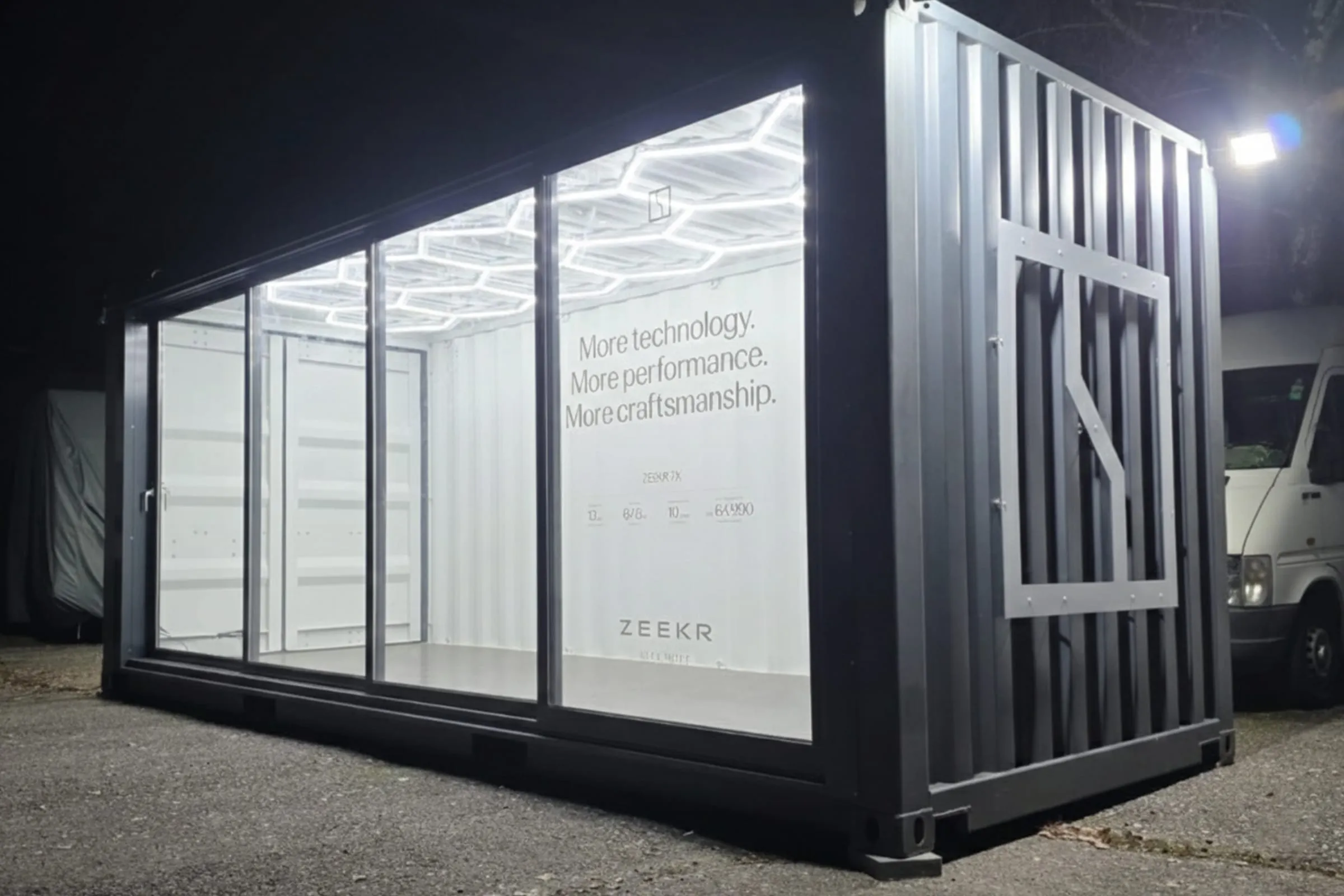 Beleuchteter Zeekr-Container bei Nacht mit leerem, weiss ausgekleidetem Innenraum und Waben-LED-Decke