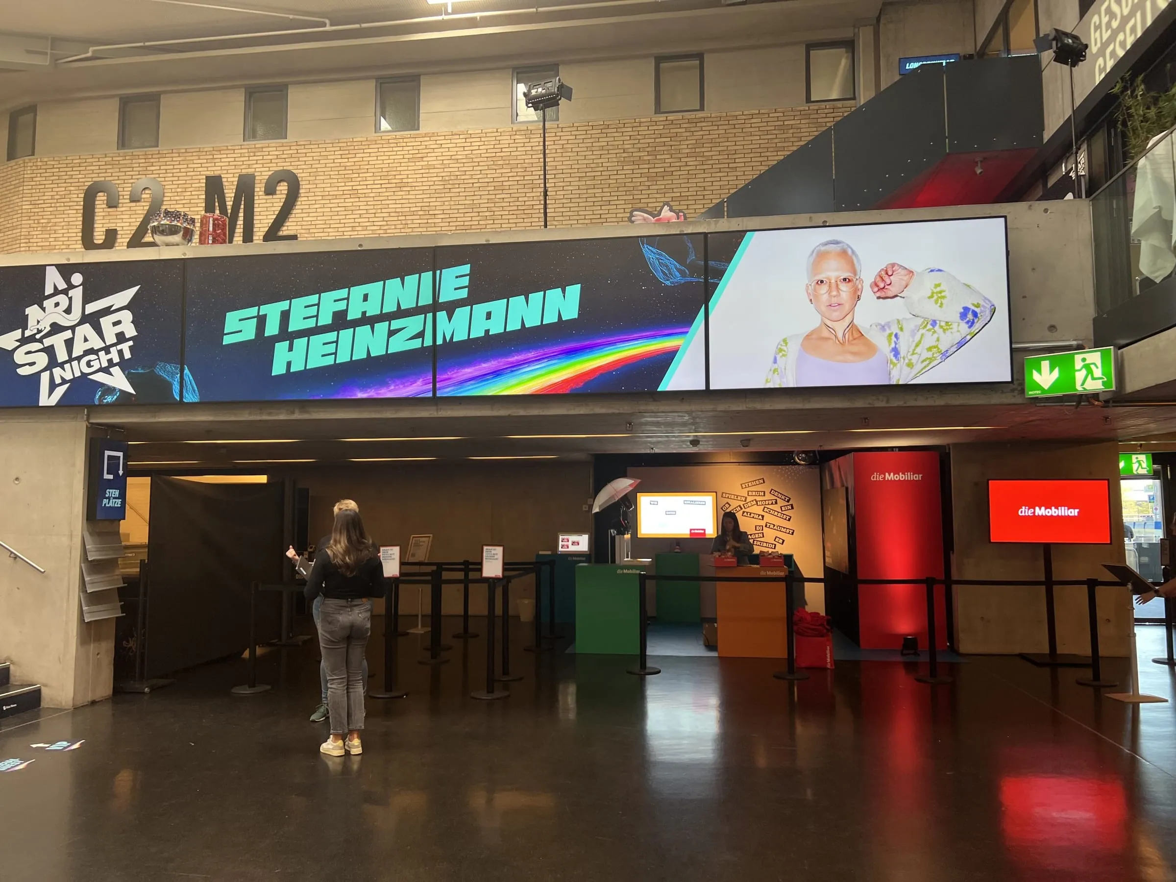 Foyer of the Hallenstadion Zürich with the Mobiliar stand under the LED wall: coloured cubes, word wall, red pillar and a screen with the Mobiliar logo