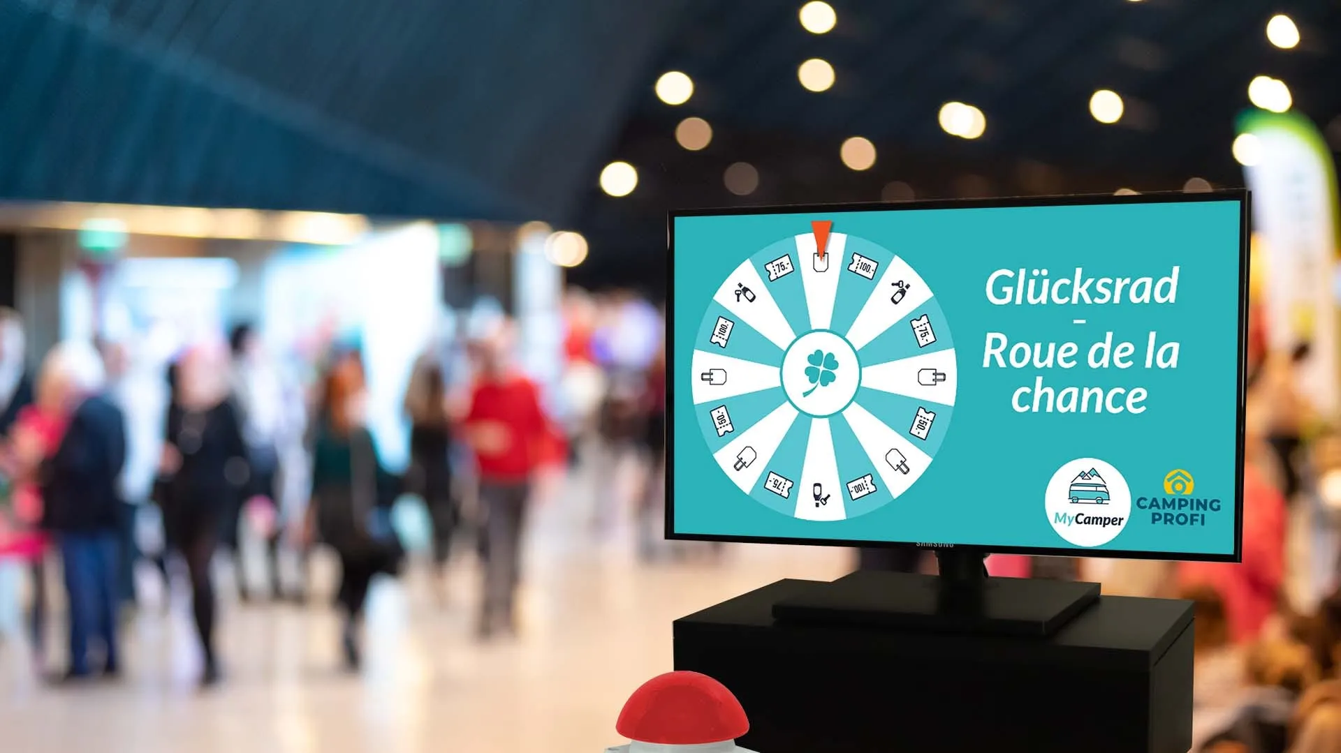 Screen with the turquoise Roue de la chance wheel of MyCamper and Camping Profi in an exhibition hall