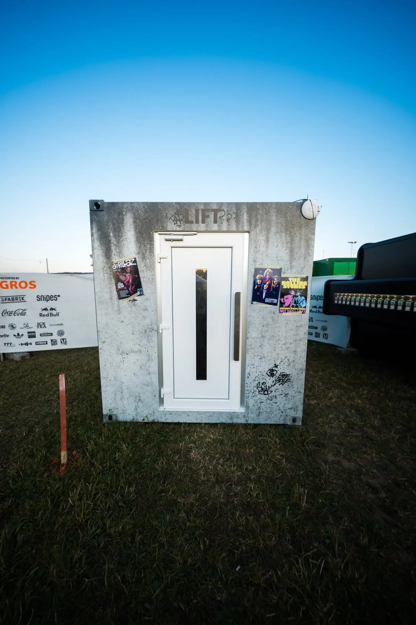 Frontansicht des Containers mit weisser Lifttür, «Lift»-Beschriftung und Postern von Gorillaz und den Rolling Stones
