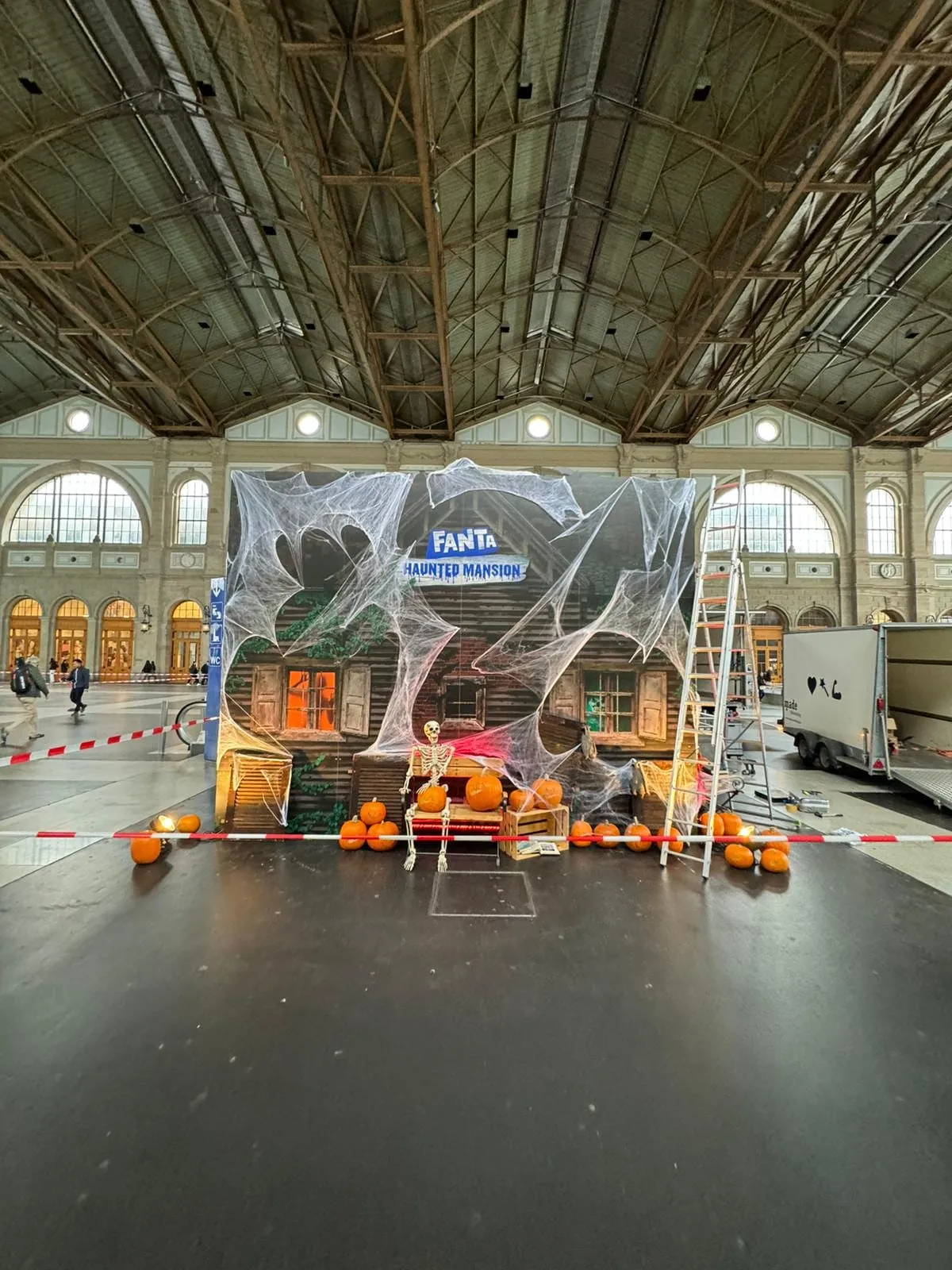 Fanta Haunted Mansion facade with cobwebs, a skeleton and pumpkins in Zürich main station, still being assembled