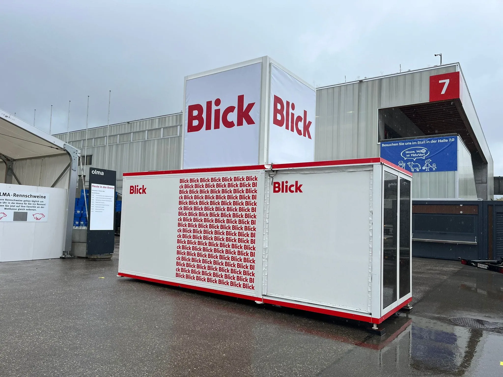 Verglaste Blick-Box mit Aufkleber «Dein Gesicht auf einer Blick-Titelseite» vor Zelten an der OLMA