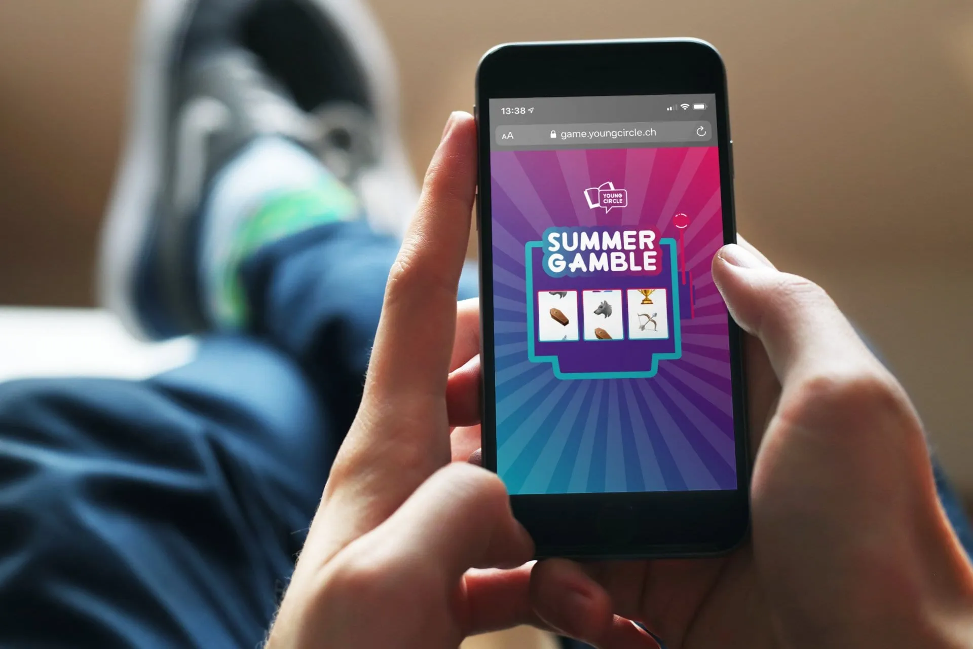 Zwei Hände halten ein iPhone mit dem Summer-Gamble-Spiel: drei Emoji-Walzen vor violett-pinkem Hintergrund