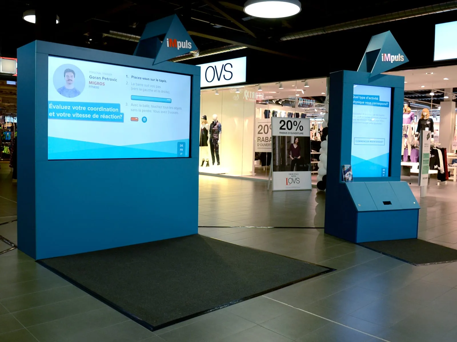 Reaktionswand und Typengenerator-Station in Blau mit Bildschirmen und schwarzer Matte im Einkaufszentrum