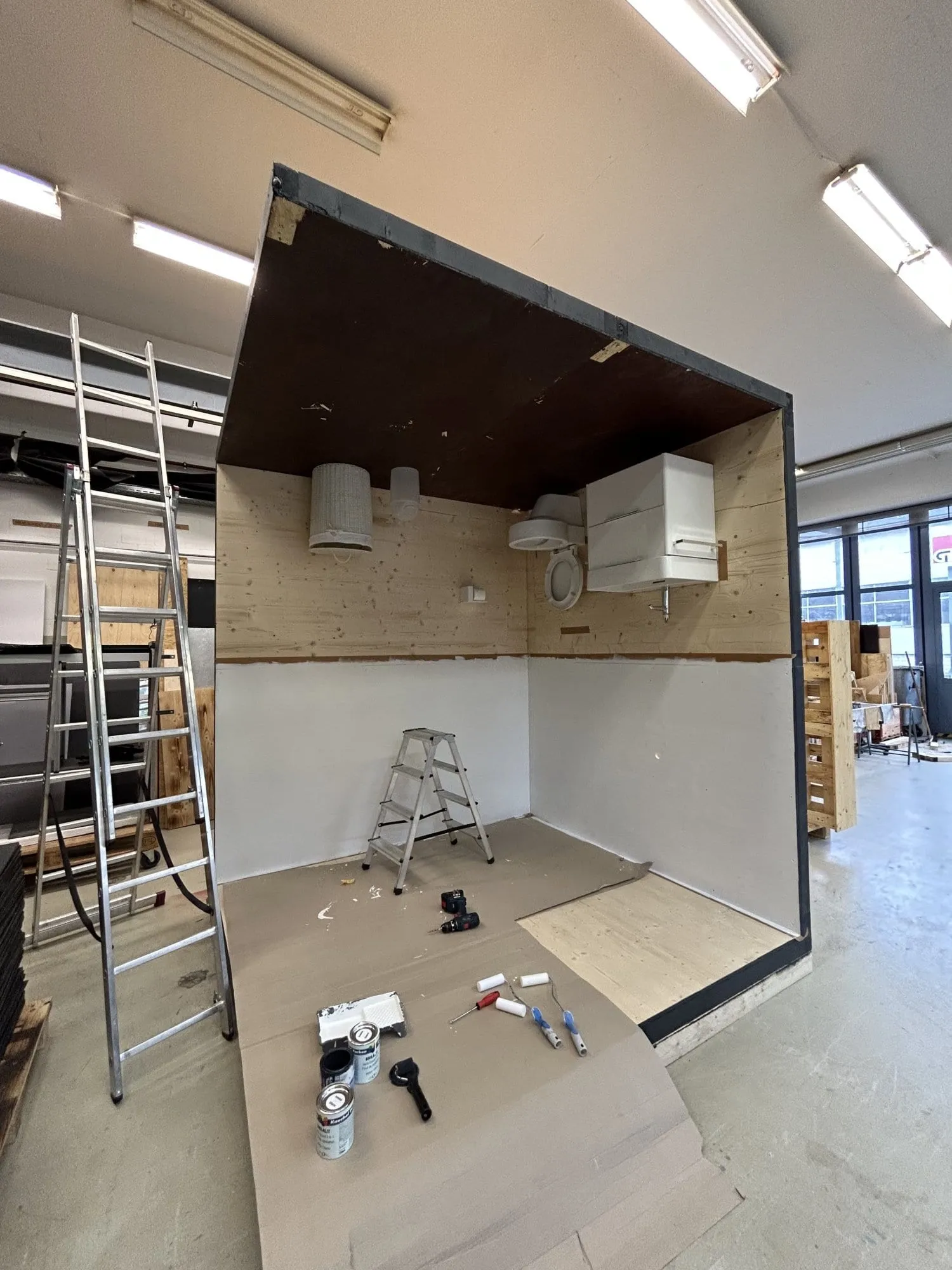 Rohbau des Upside-Down-Bads in der Werkstatt: WC und Waschtisch an der Decke montiert, Leitern und Farbtöpfe