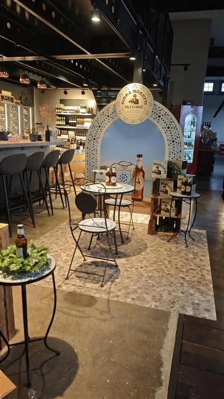 Corner im Laden neben einer Bar mit Hockern, Bierflasche auf dem Mosaiktisch und Holzkisten mit Moretti-Kartons