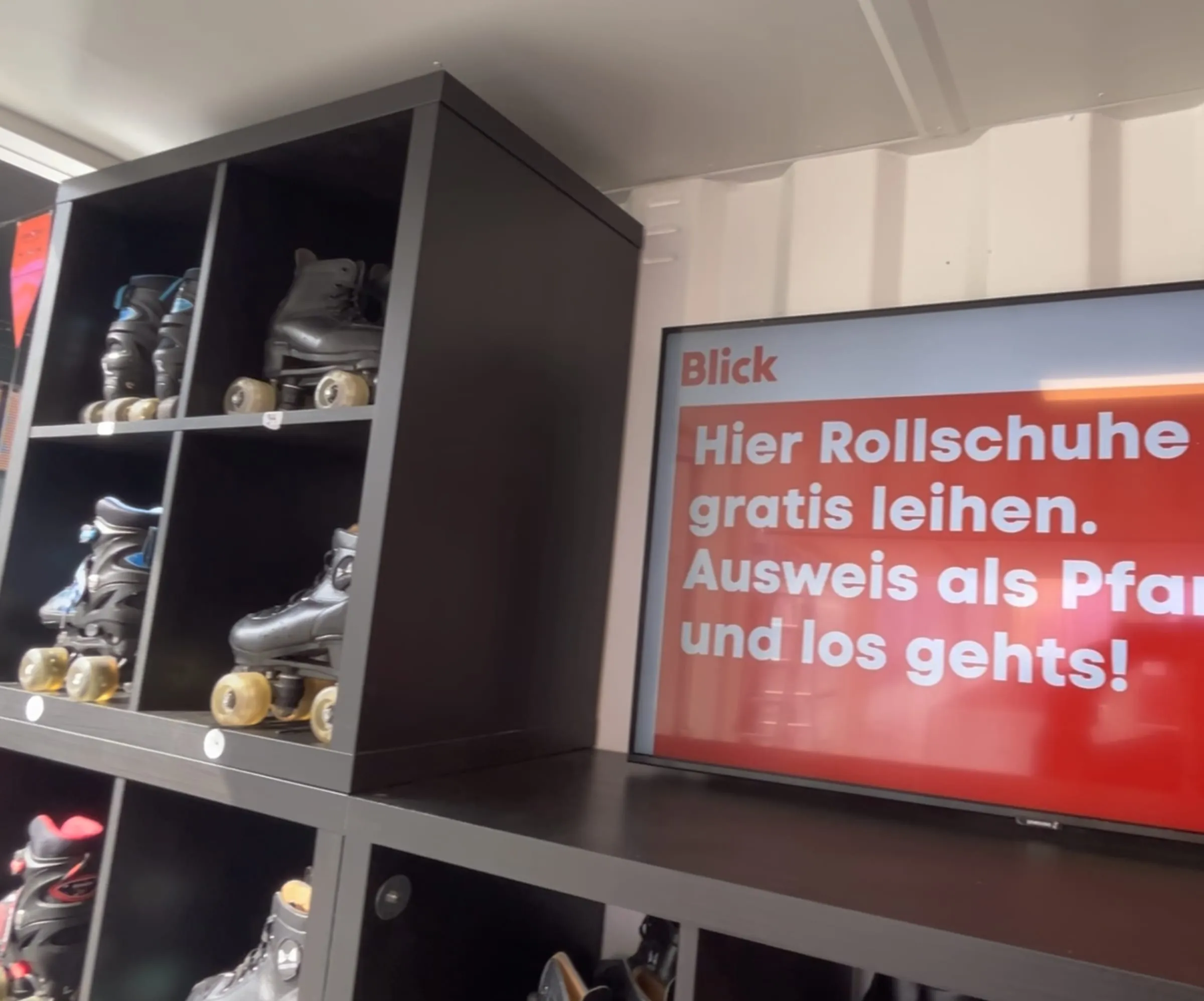 Regal mit Rollschuhen im Container, daneben ein Bildschirm mit dem Hinweis «Hier Rollschuhe gratis leihen»